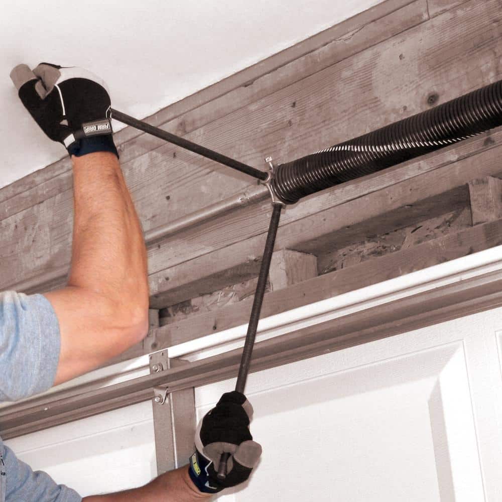 Person wearing gloves adjusting a garage door torsion spring system