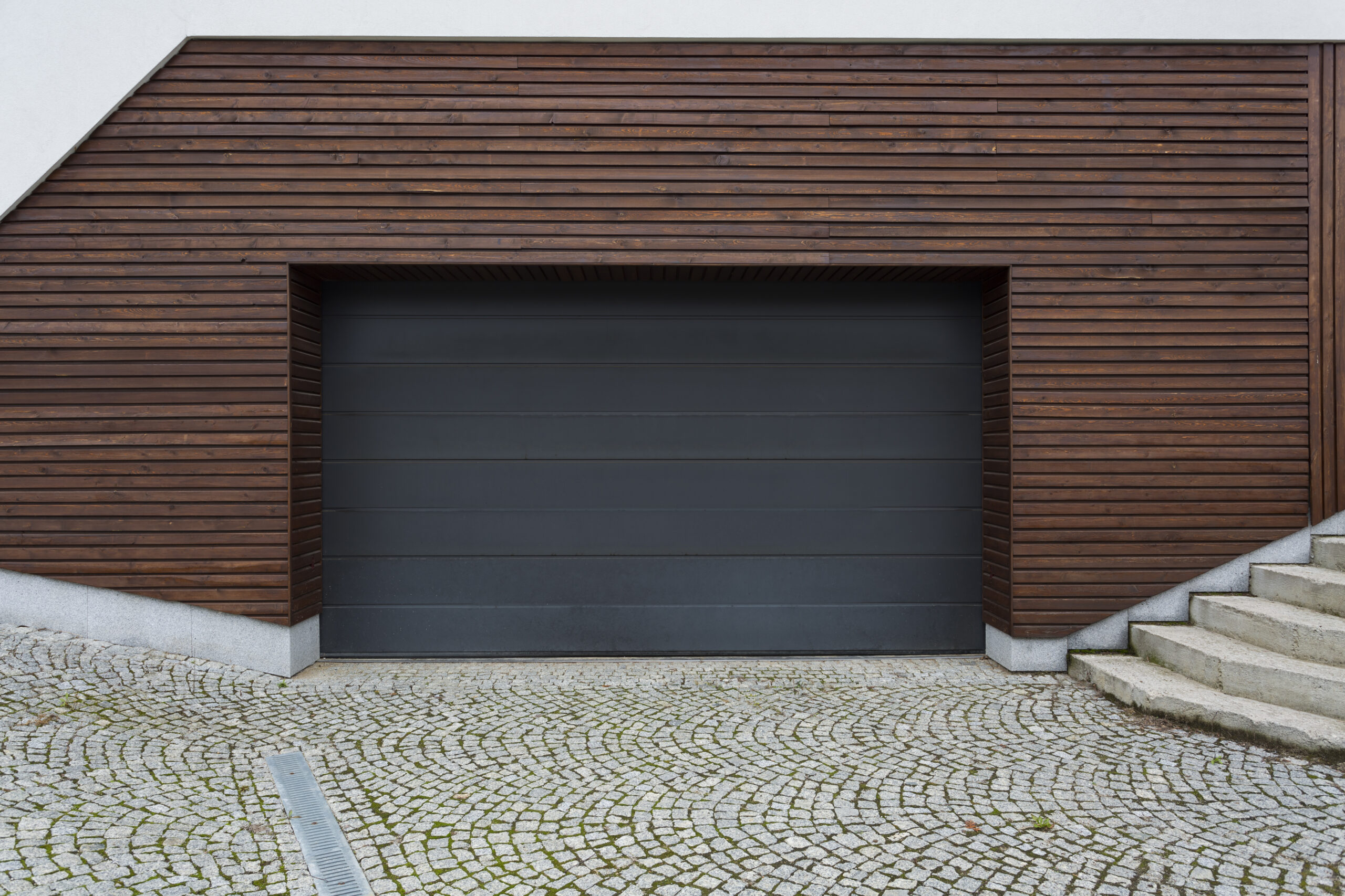 Modern house with a dark gray garage door and wooden siding.