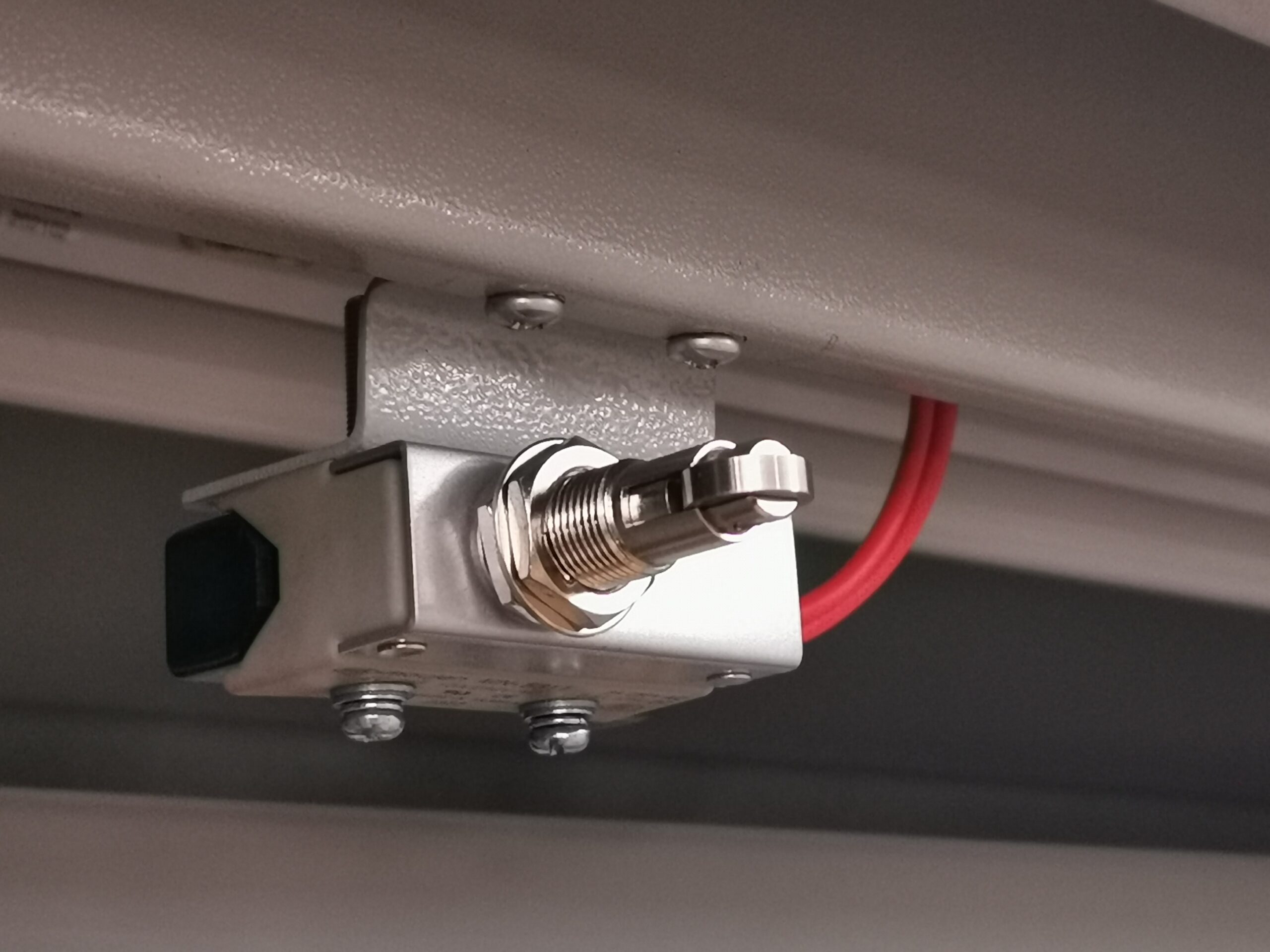 Close-up of a silver metal switch with a red wire attached.