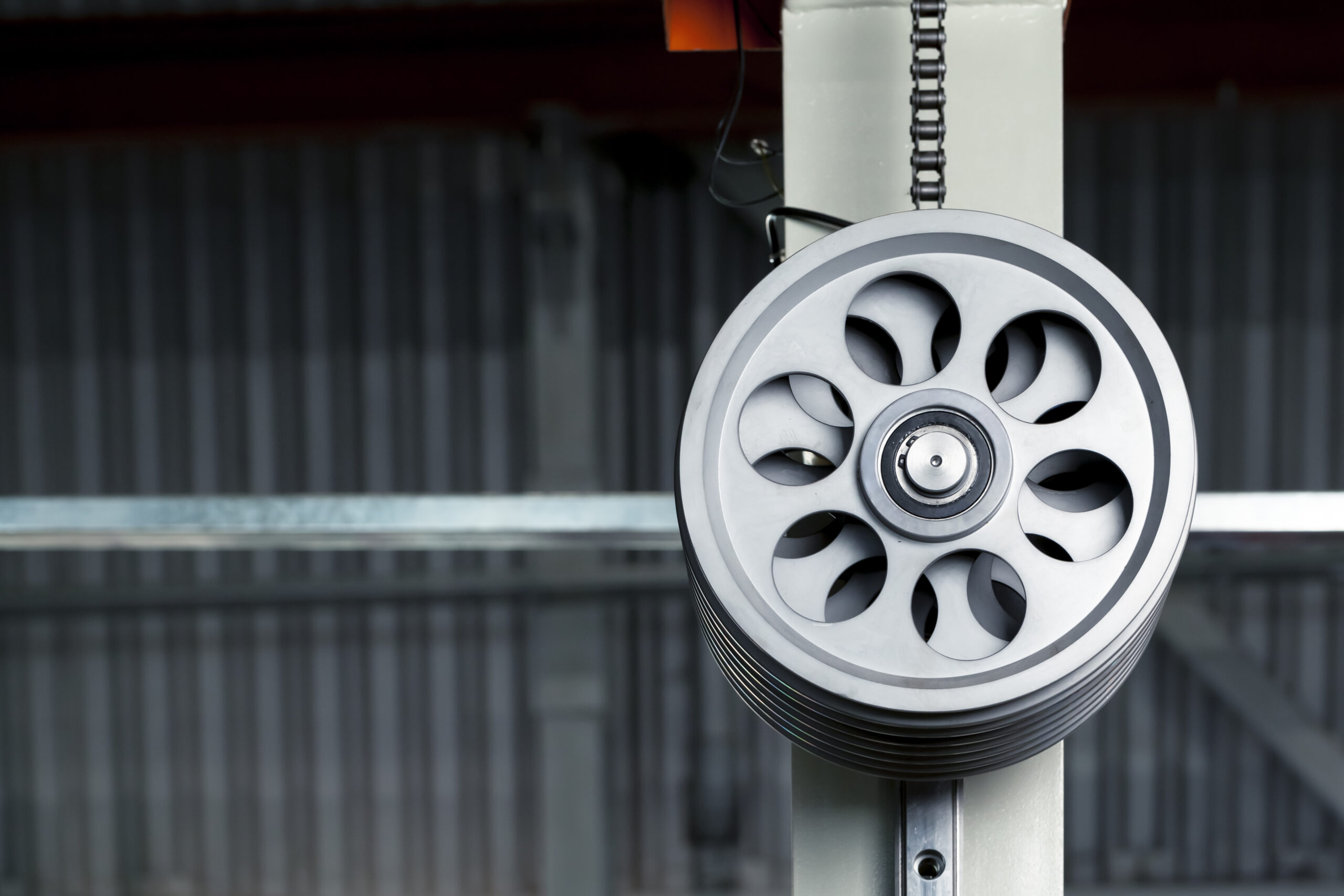 Close-up of a metal pulley wheel with a chain attached to it.