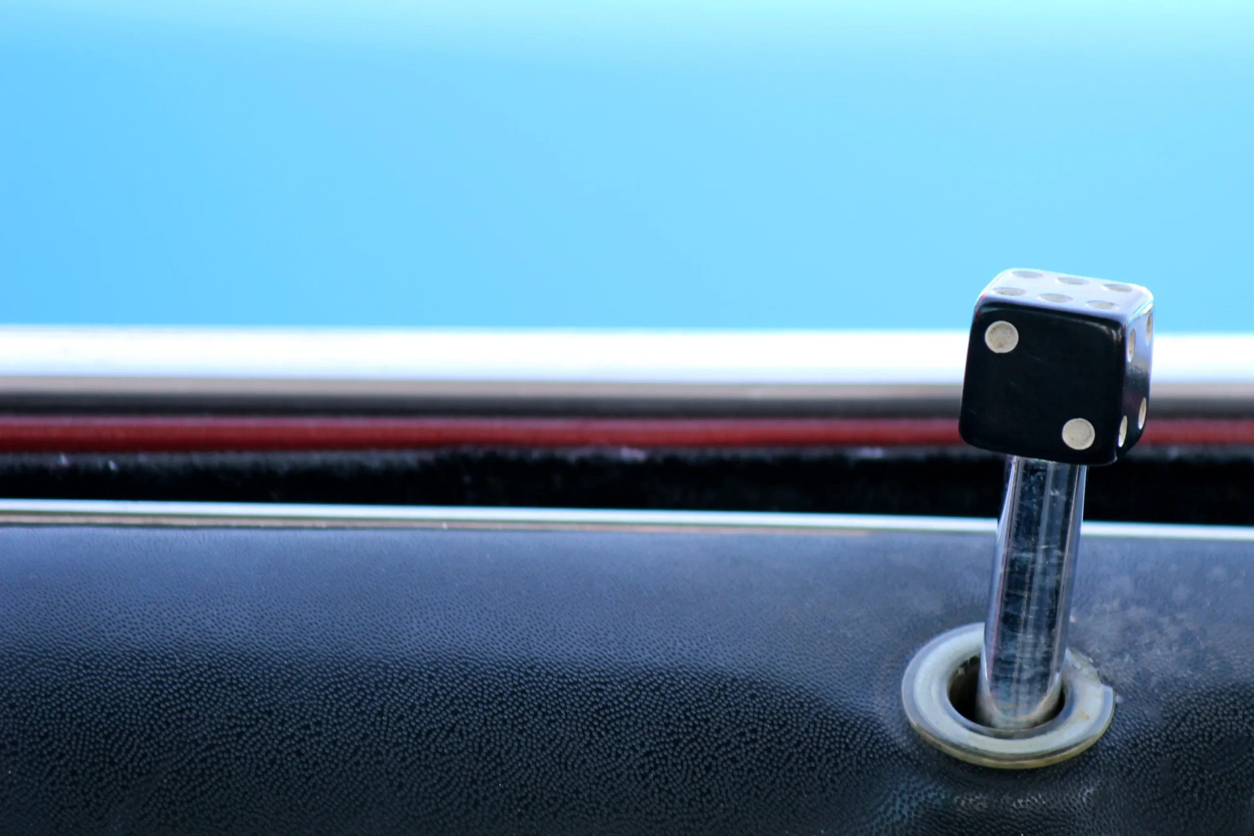 Black dice on a car door lock with a blue background.