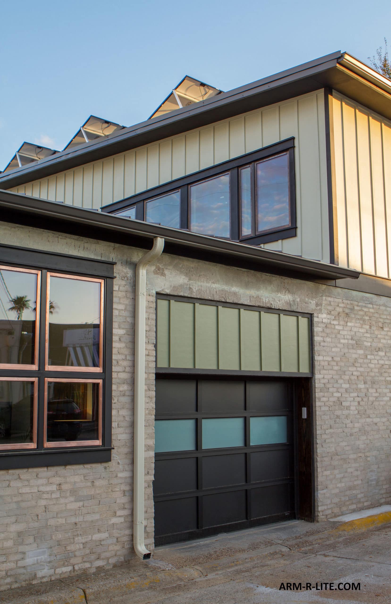Modern building with light brick, dark trim, large windows, and a garage door.