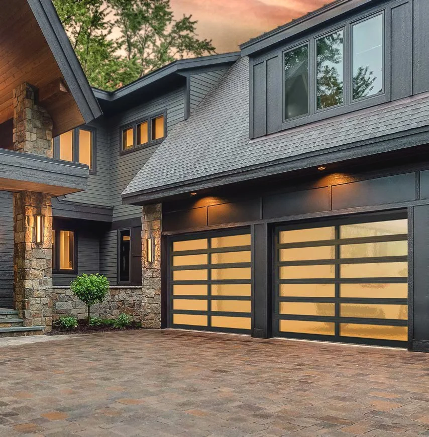 Modern house with dark siding, stone accents, and two glass garage doors.