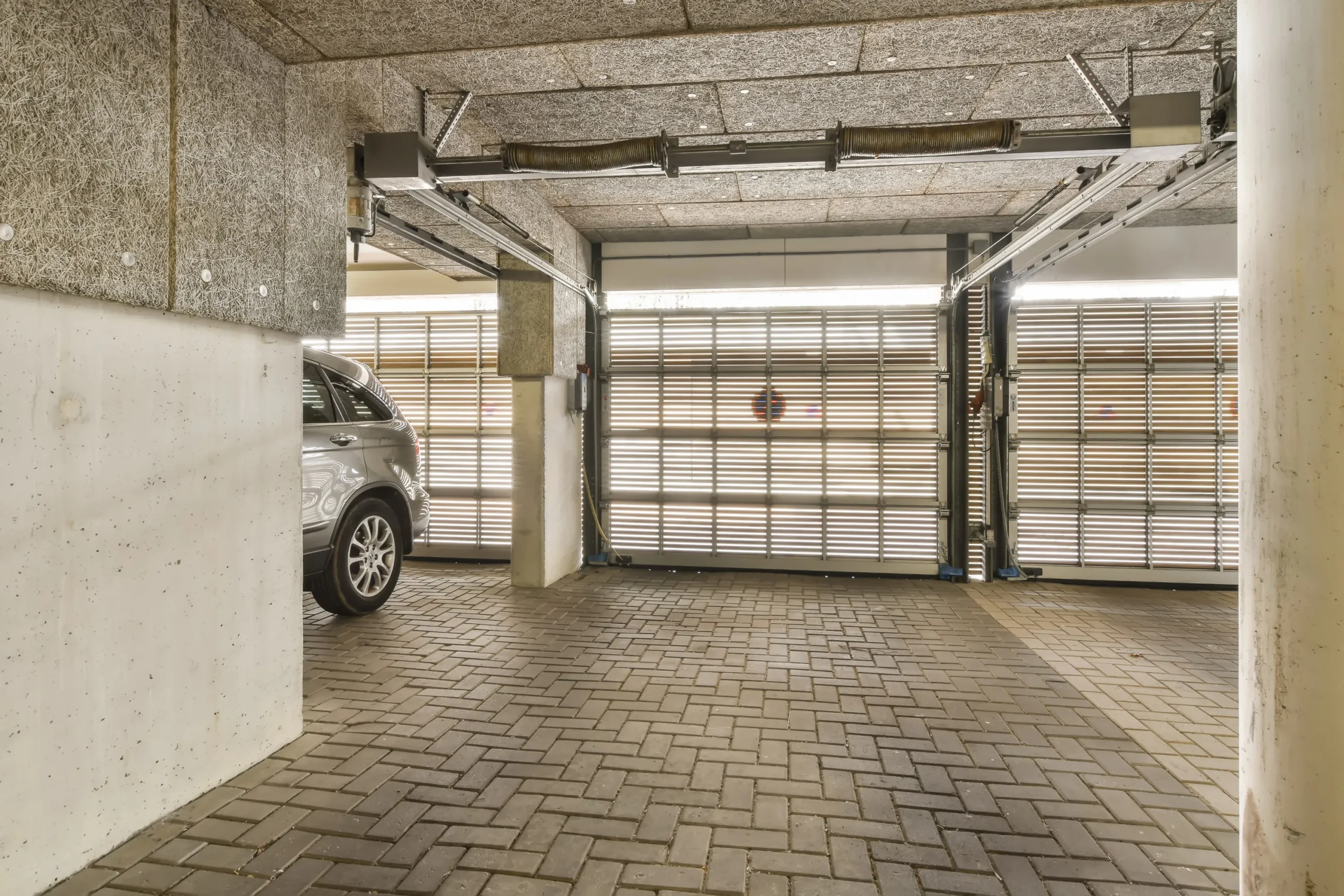 Car in a garage with closed doors and brick floor