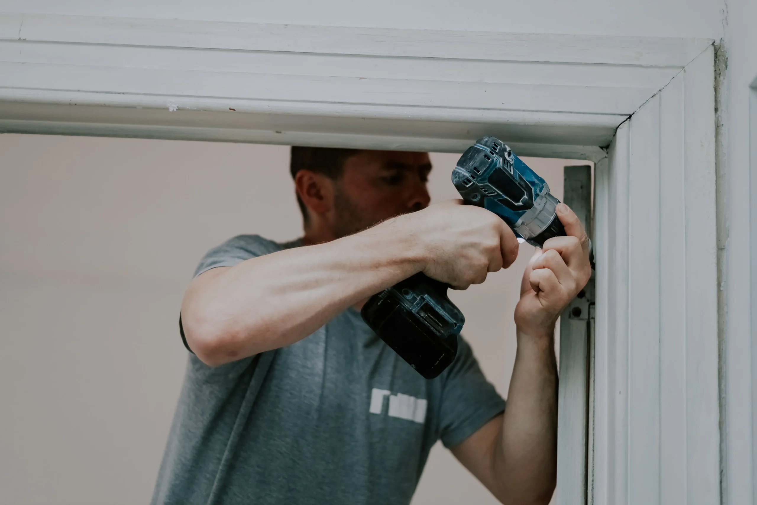 Man using a drill on a door frame, focused on home improvement.