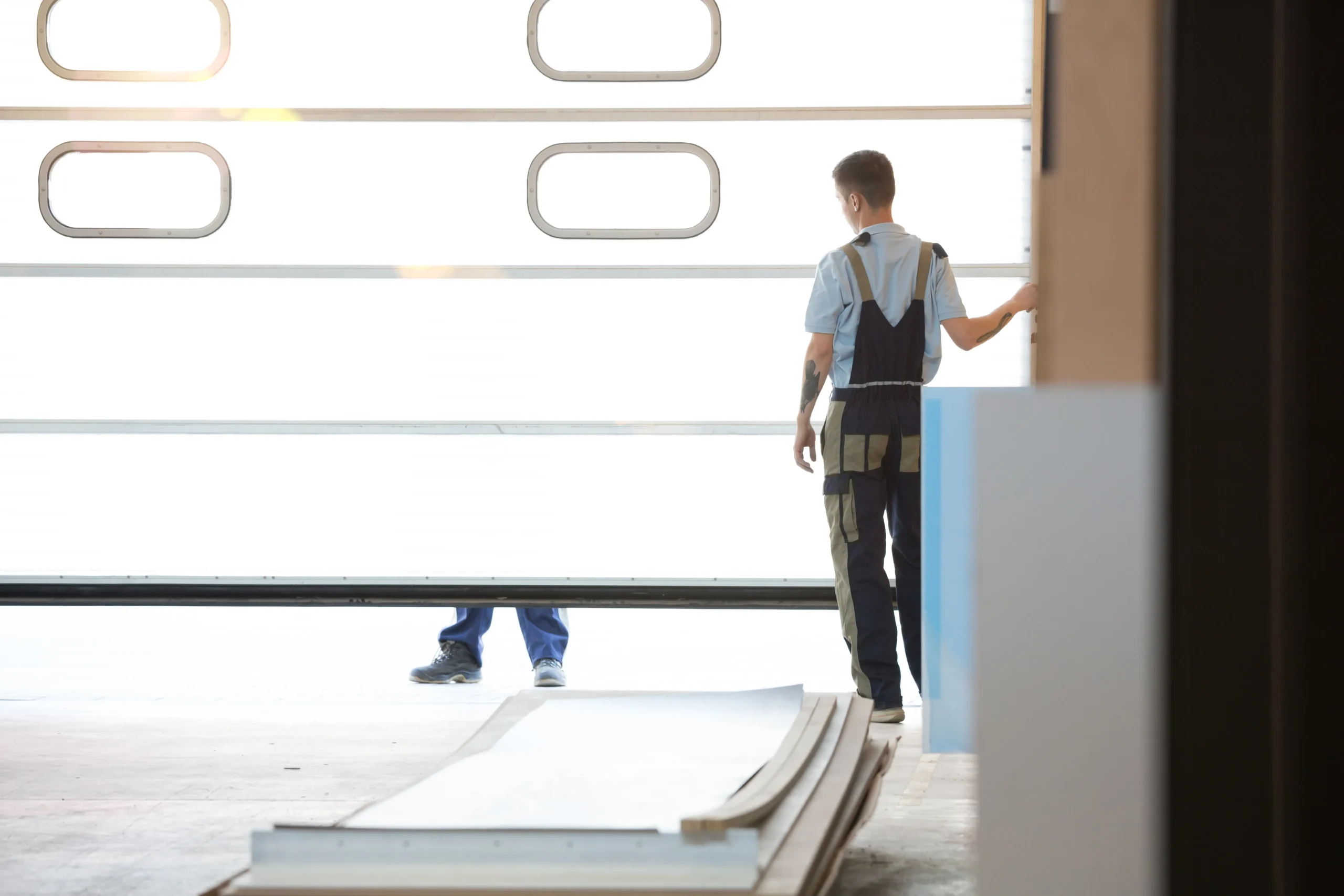 Two workers installing a white garage door with rectangular windows
