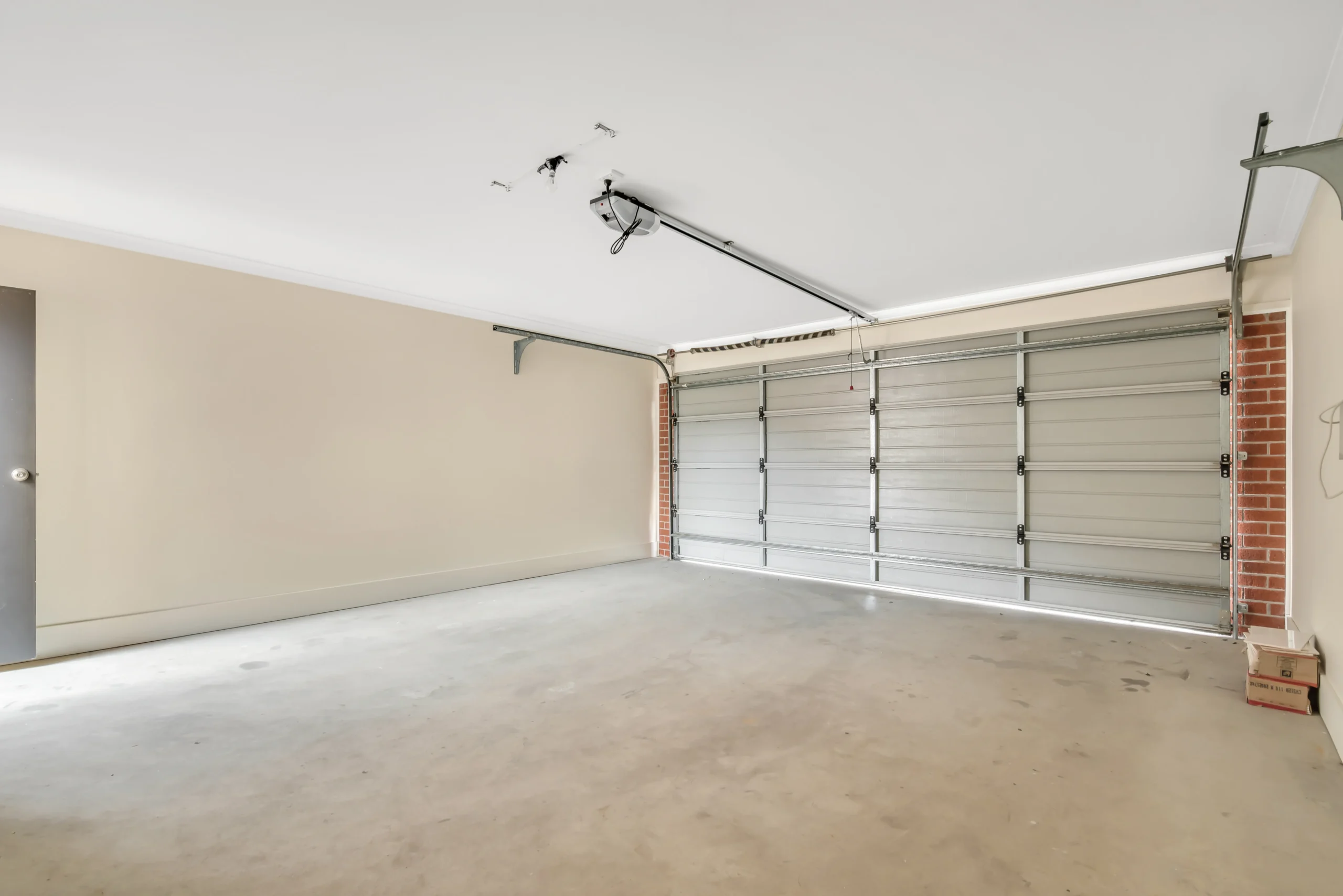 Empty garage with a closed garage door and light beige walls.