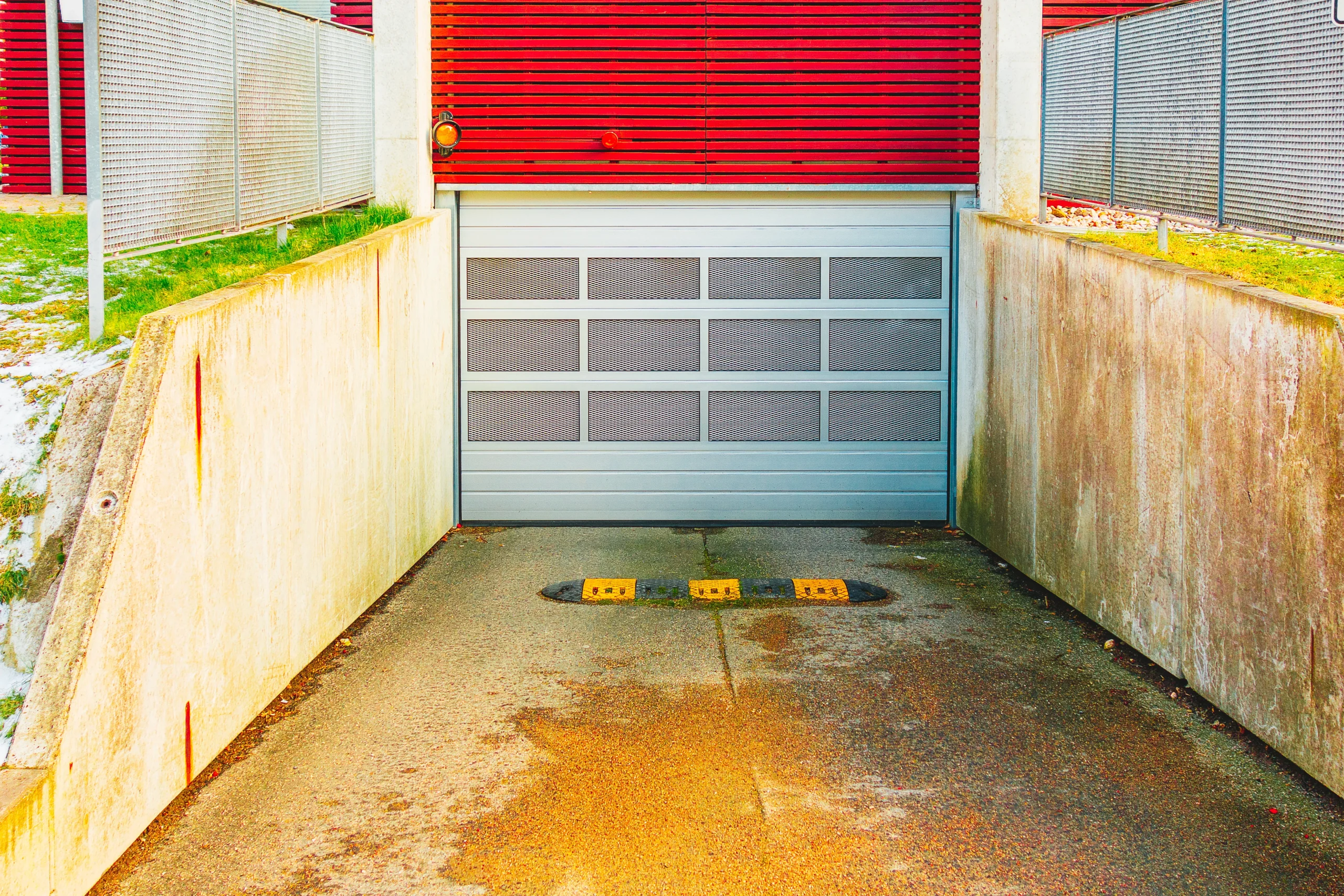 Underground garage entrance with a closed gray door and red wall.