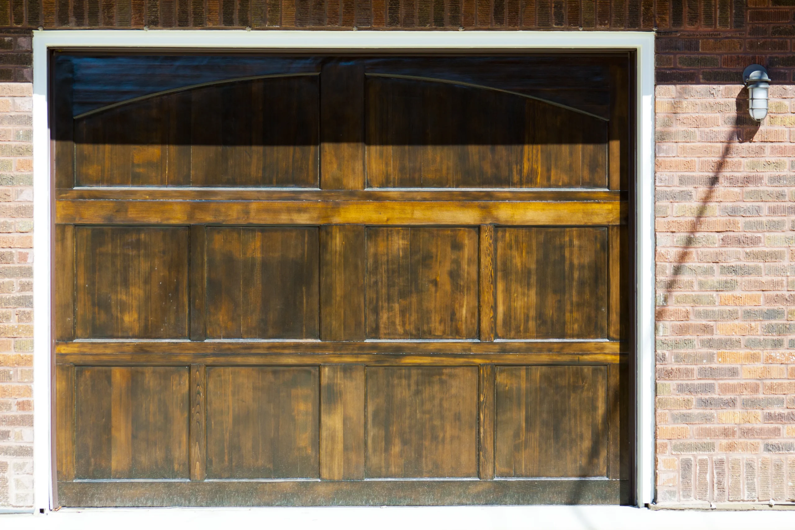 Close-up of a wooden garage door with a brick wall.