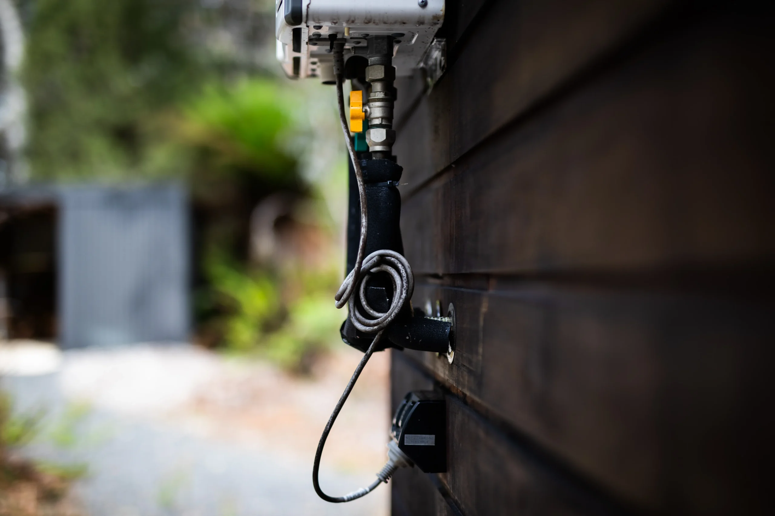 Close-up of a power cord plugged into a dark wooden wall.