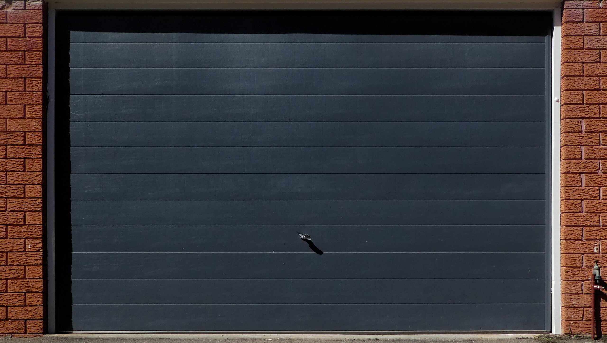 Dark grey garage door with horizontal panels and a black handle