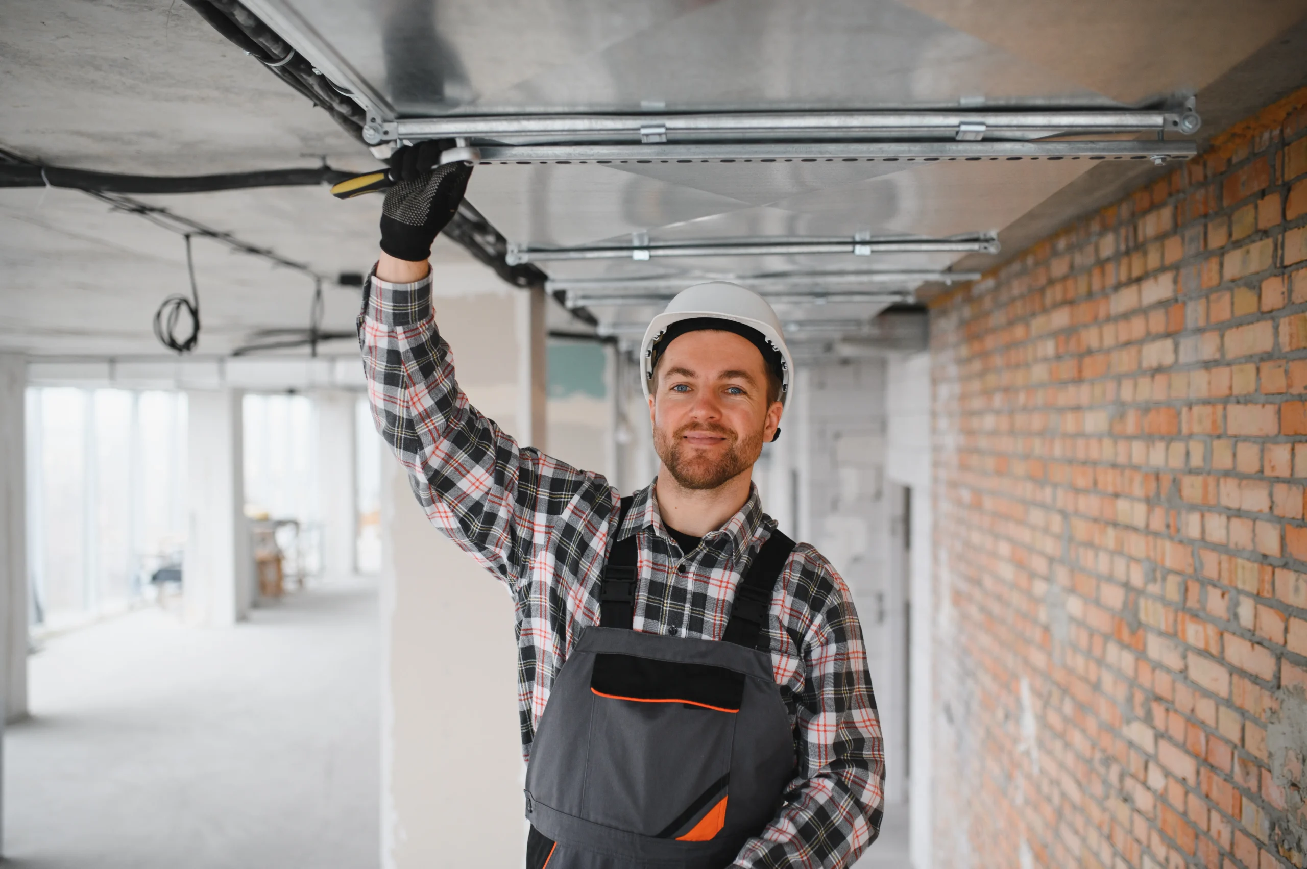 Man in hard hat installing ceiling fixtures in a construction site