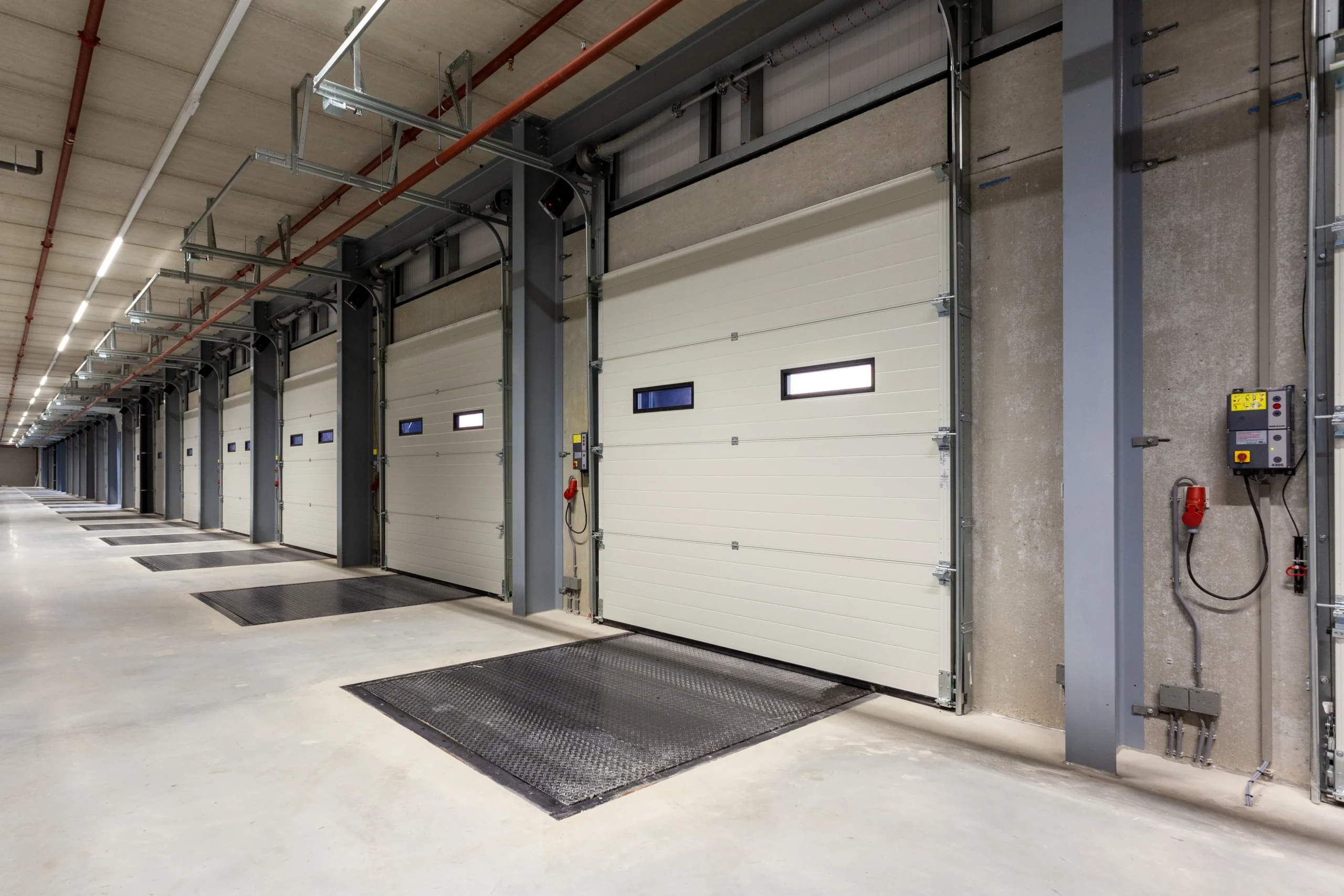 Row of white industrial loading dock doors in a modern warehouse.