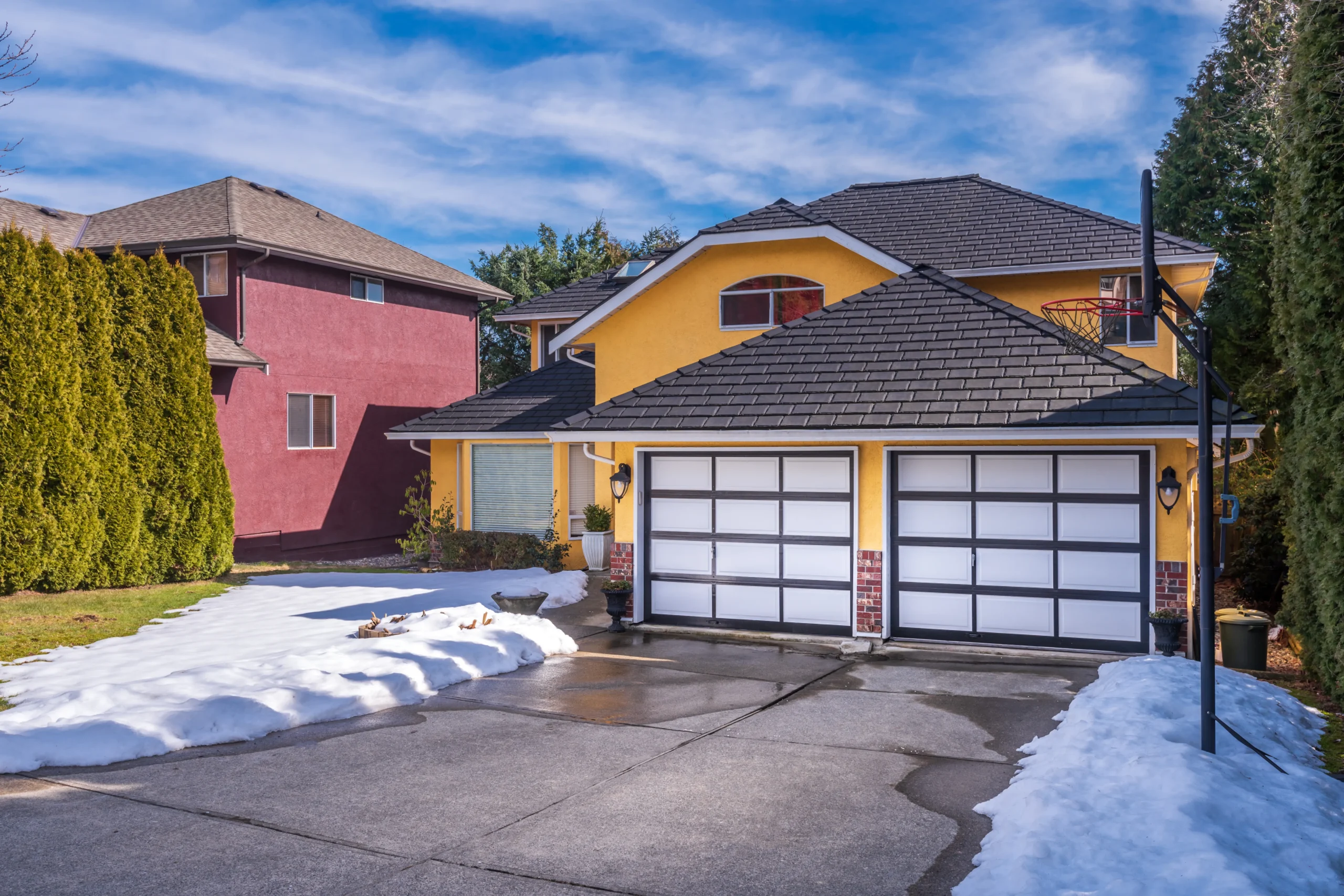 Yellow house with two-car garage and snow on the ground