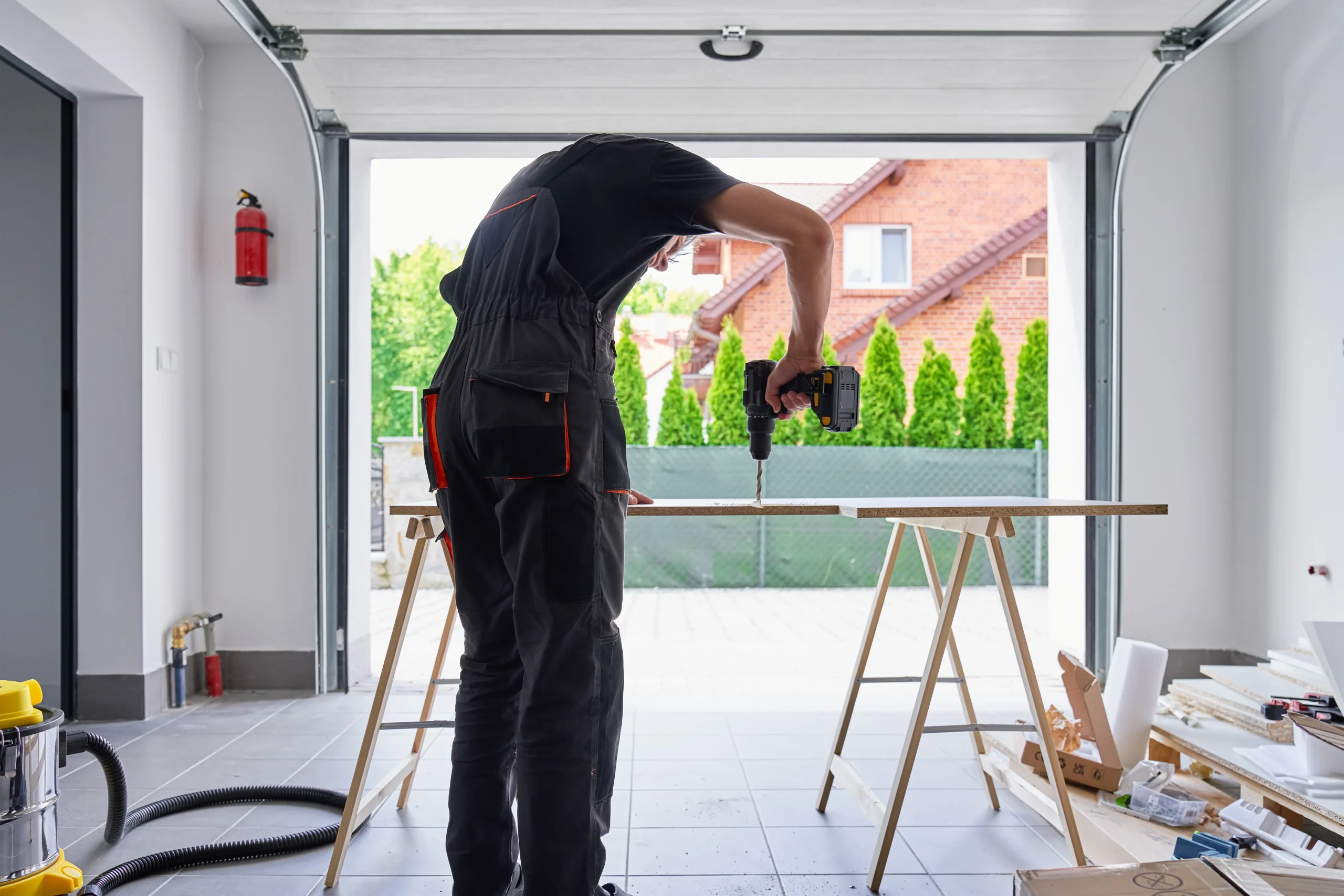 Man drilling wood in garage with open door