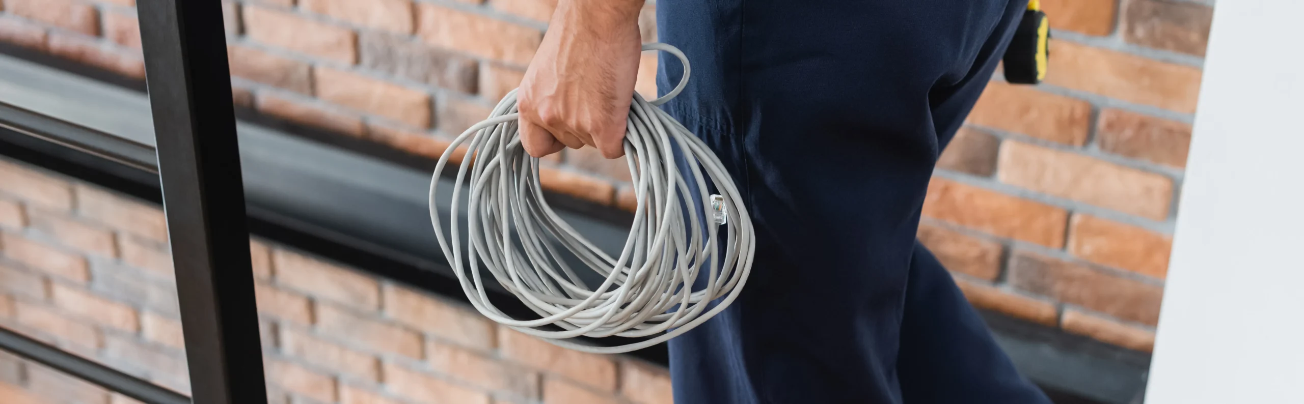 Person holding a coiled grey cable with an RJ45 connector