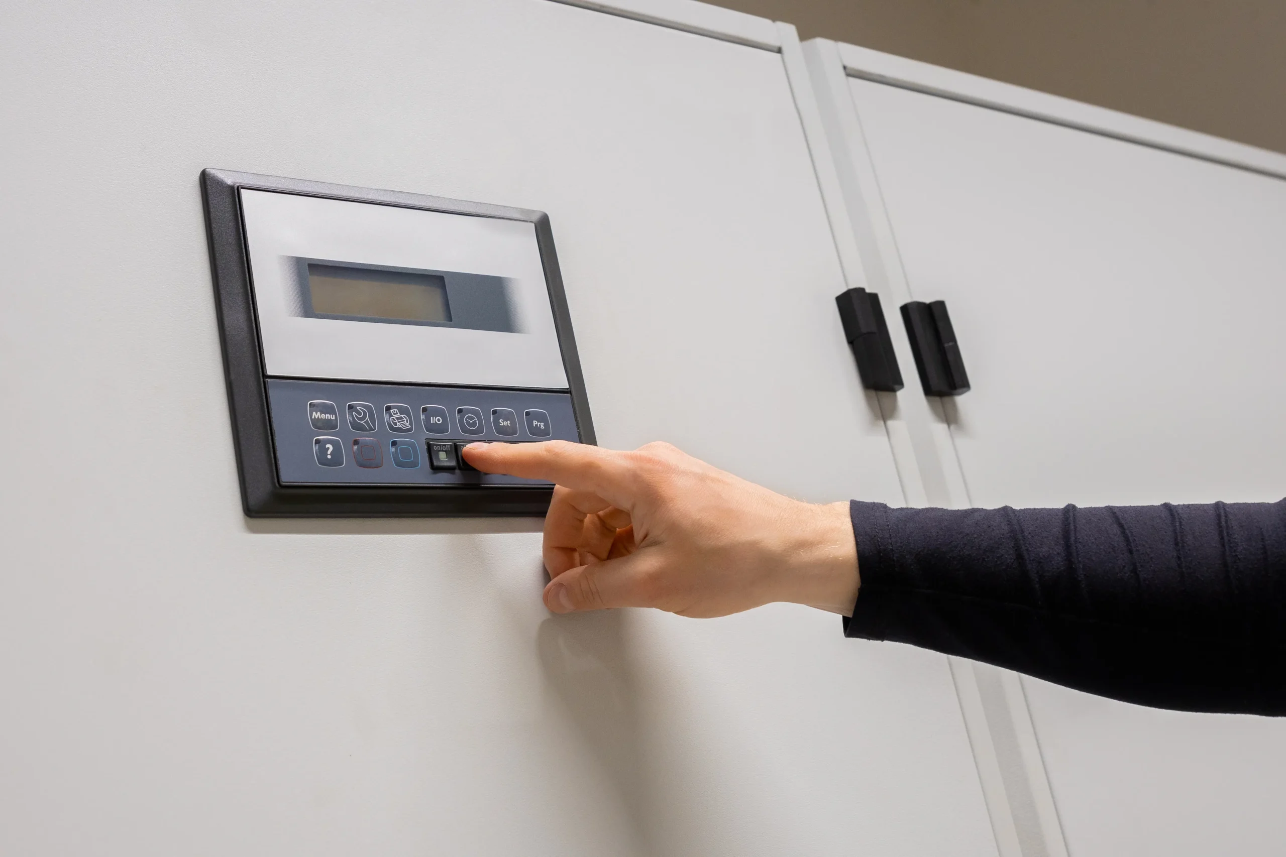 Hand pressing a button on a control panel with a digital display.