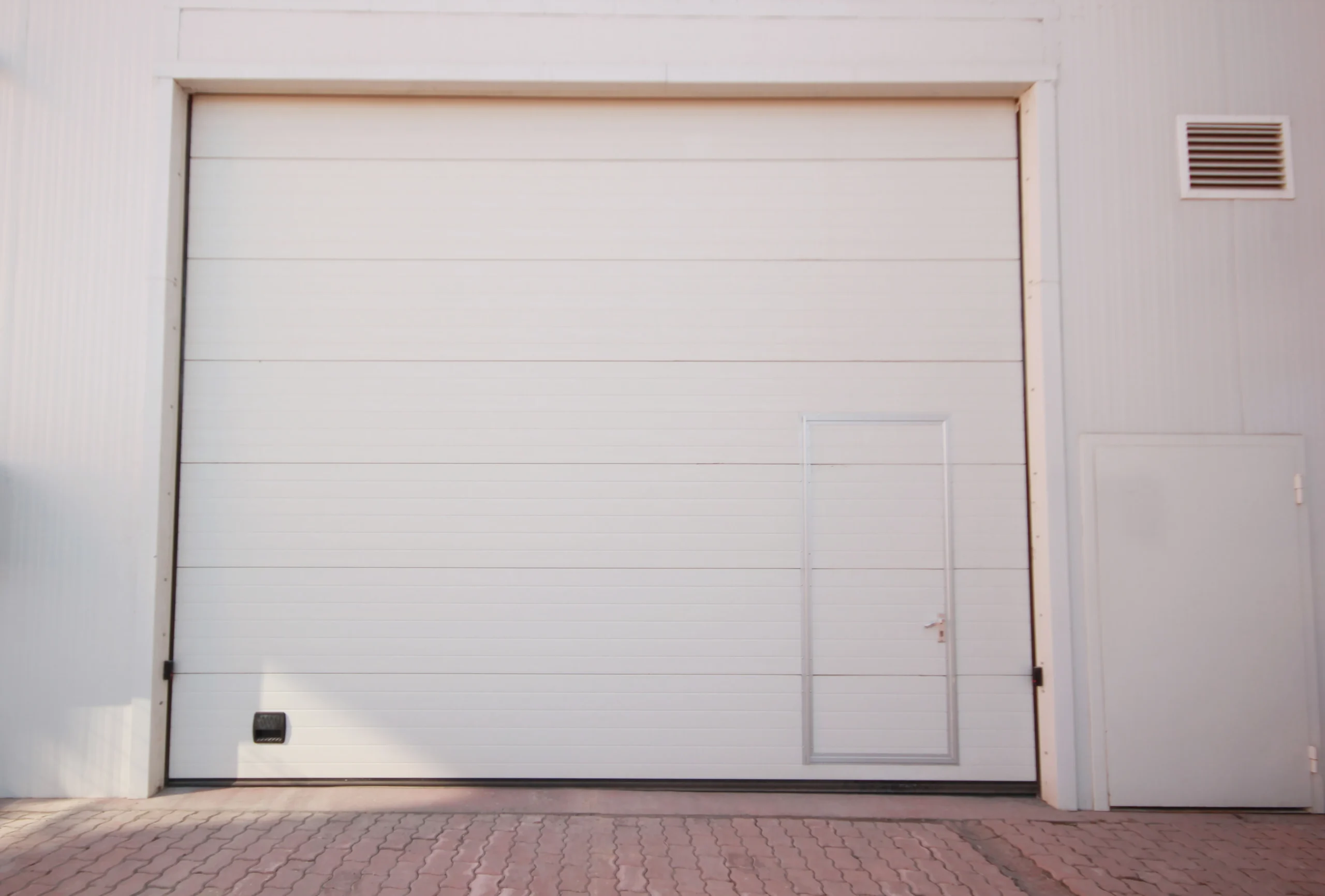 Large white garage door with a small door and a side door.
