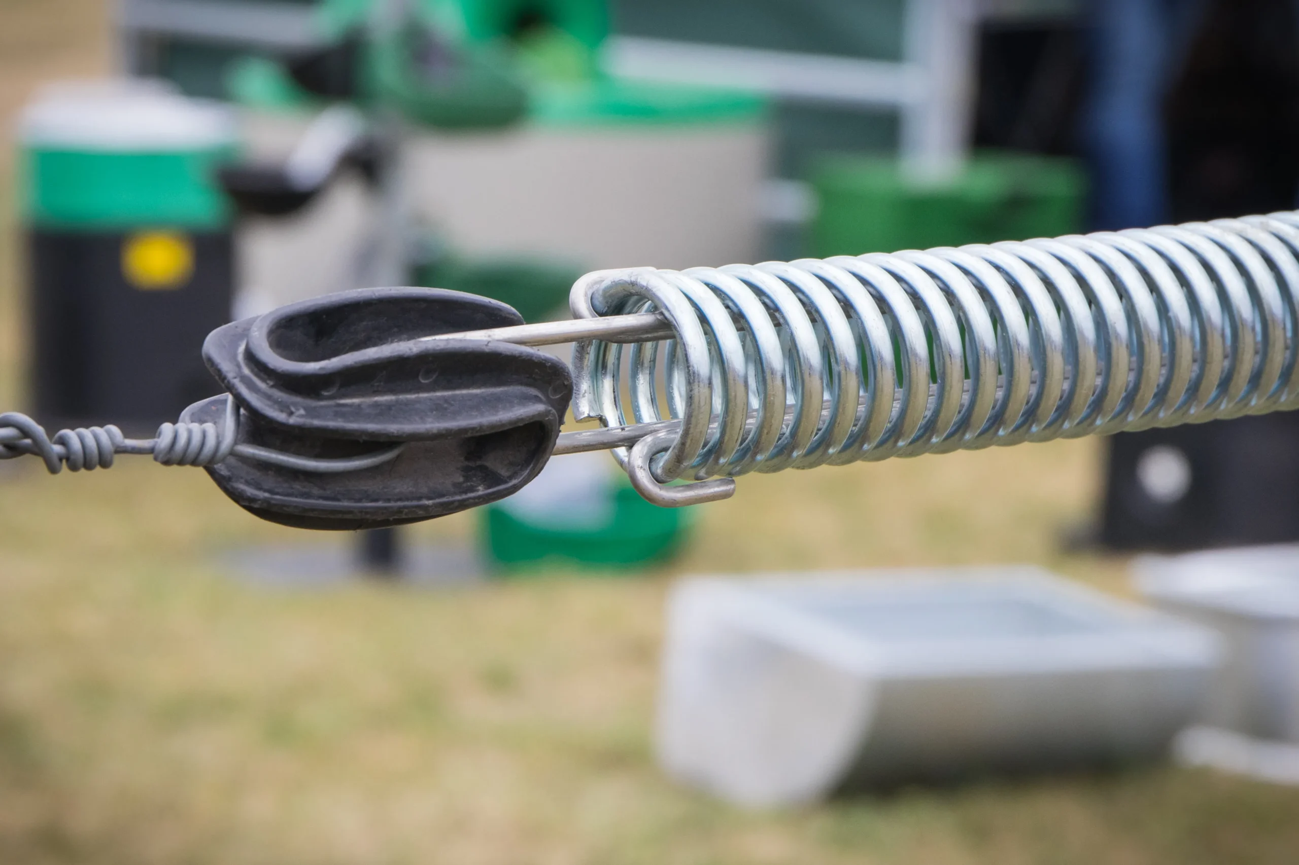 Close-up of a metal spring attached to a black plastic insulator and wire.