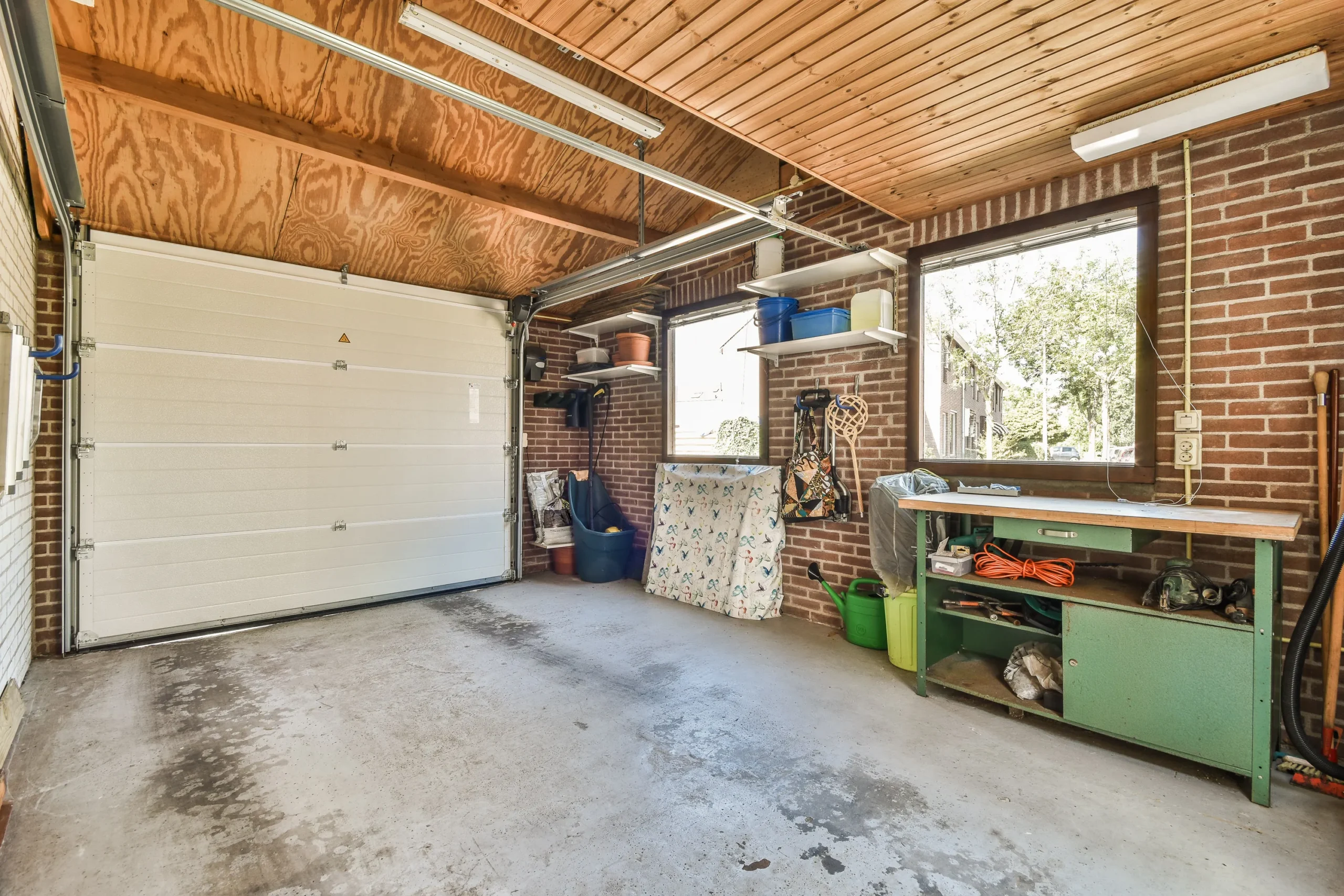 A garage with a white door, brick walls, and a wooden ceiling.