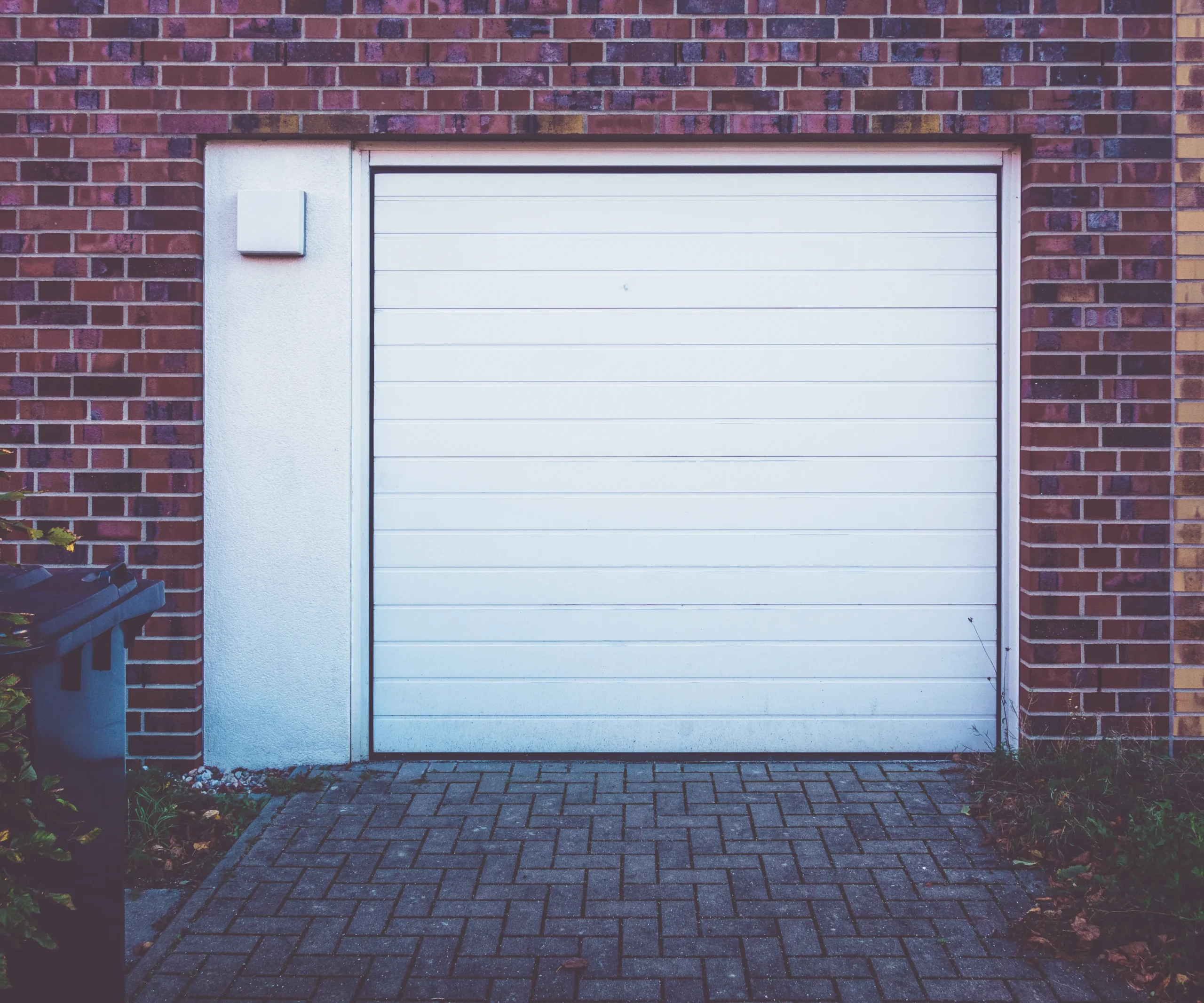 White garage door on a brick building with a paved driveway