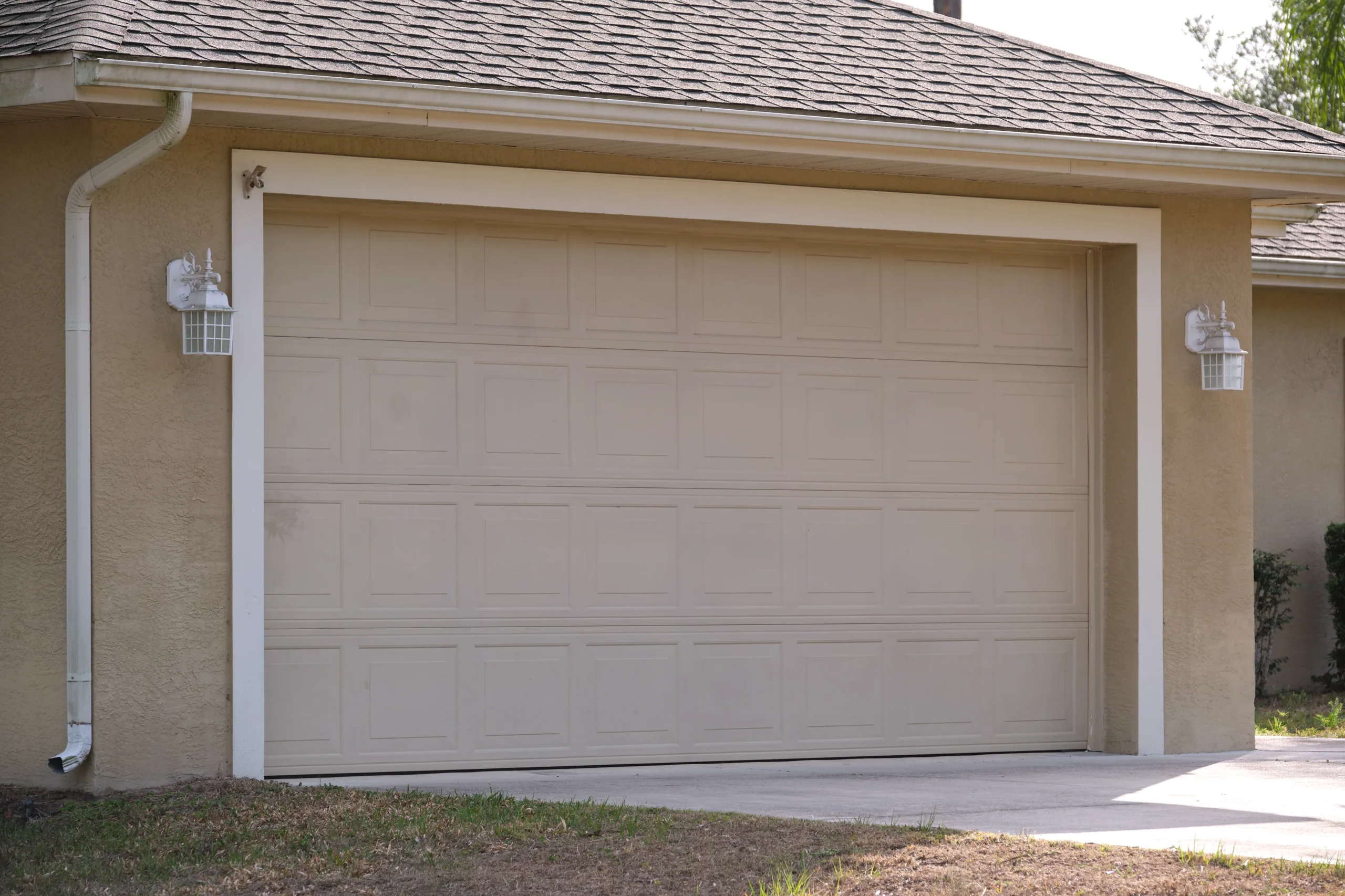 Beige garage door with square panels on a light brown house