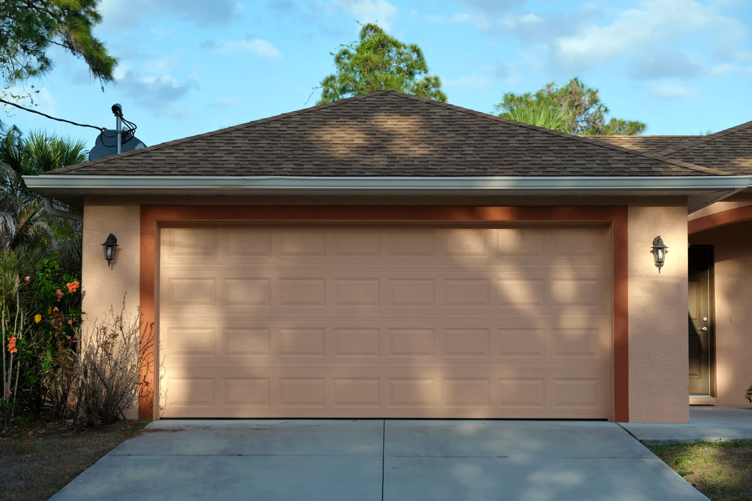 Front view of a house with a beige garage door and two outdoor lights.