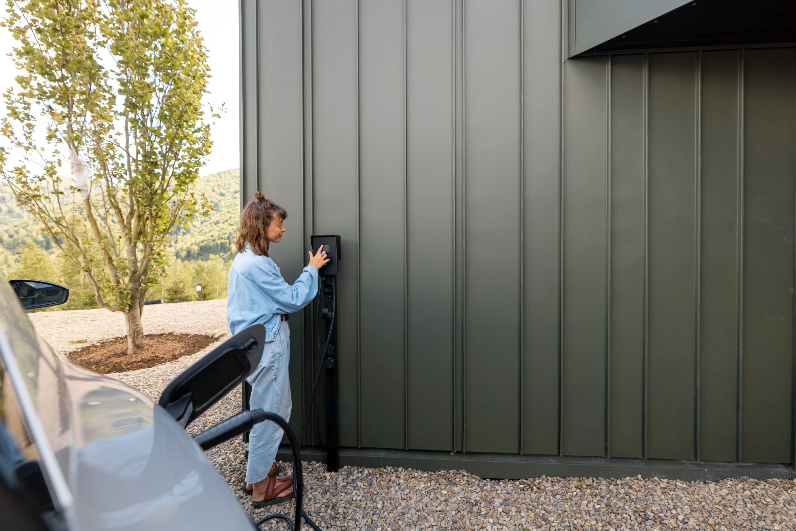 Woman charging an electric car at a modern charging station outdoors