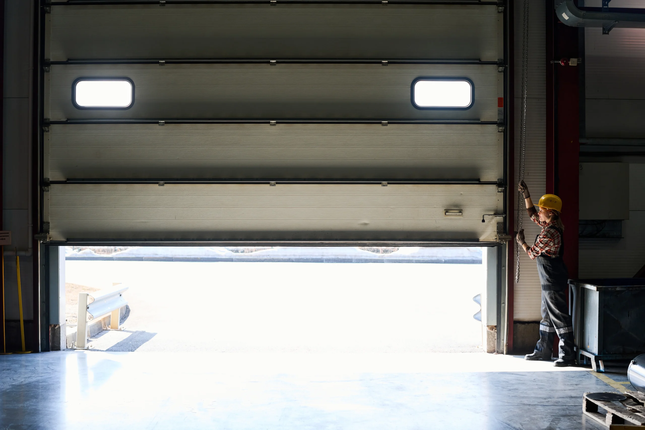 Worker opening a large garage door with windows