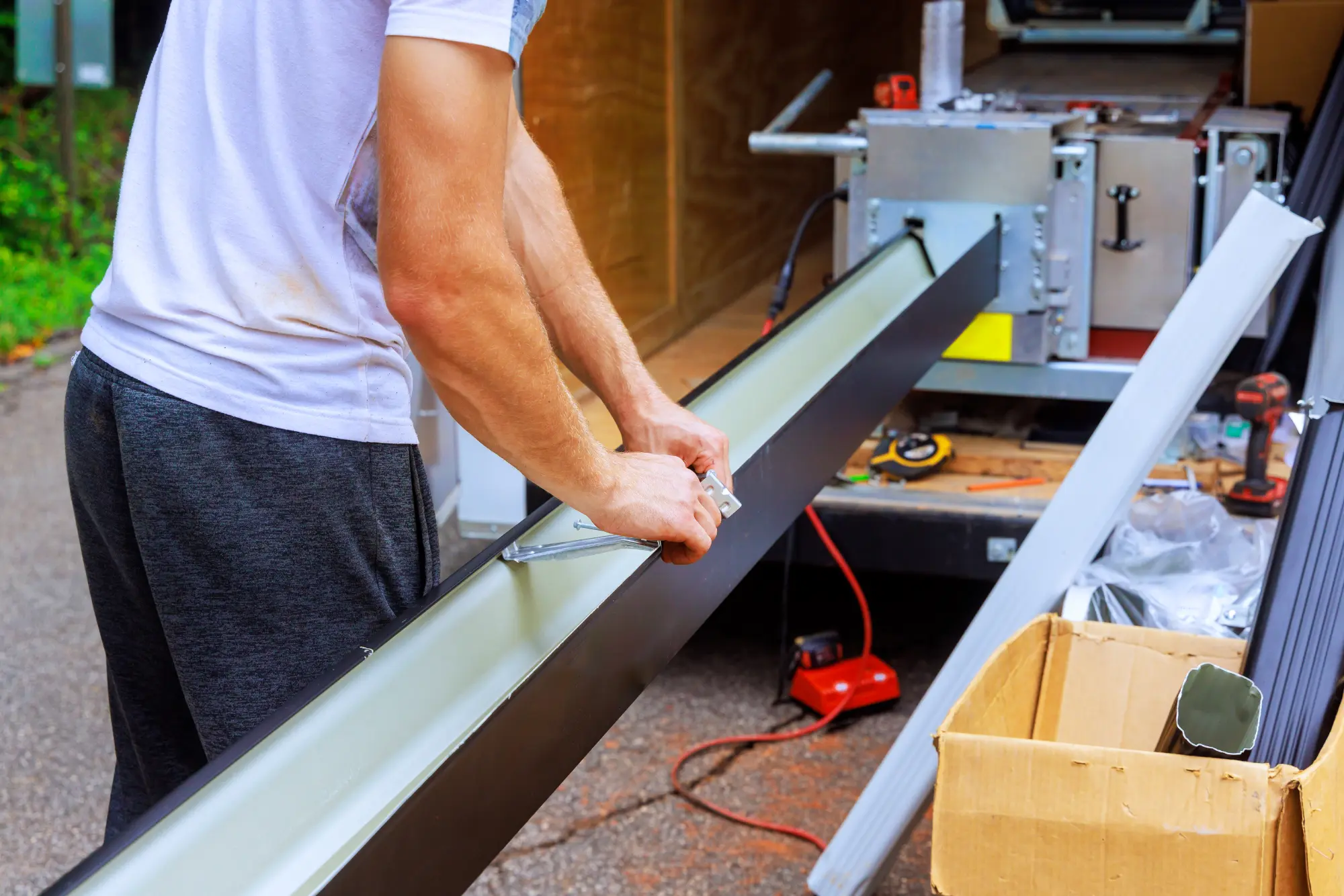 Man installing a new dark rain gutter on a building