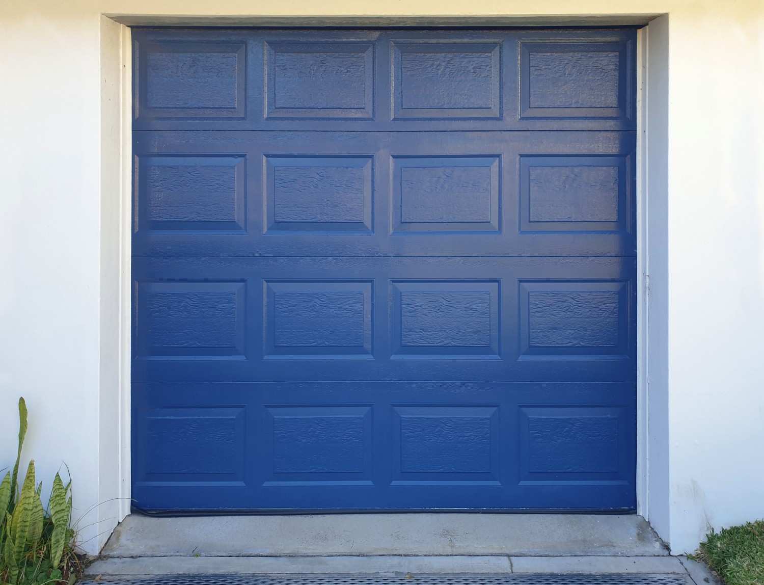 A blue garage door with rectangular panels and a textured finish.