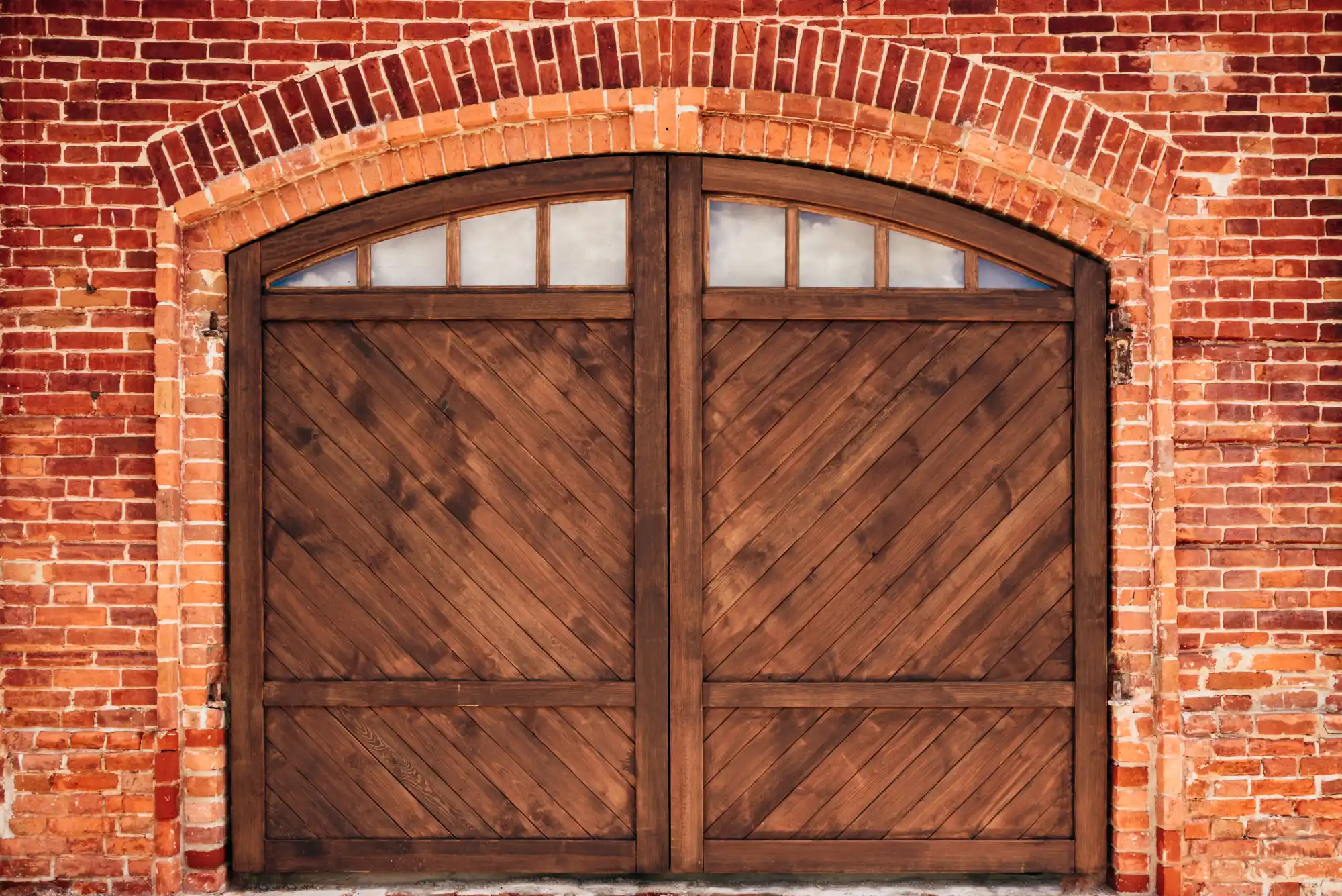 Arched wooden barn doors set in a red brick wall