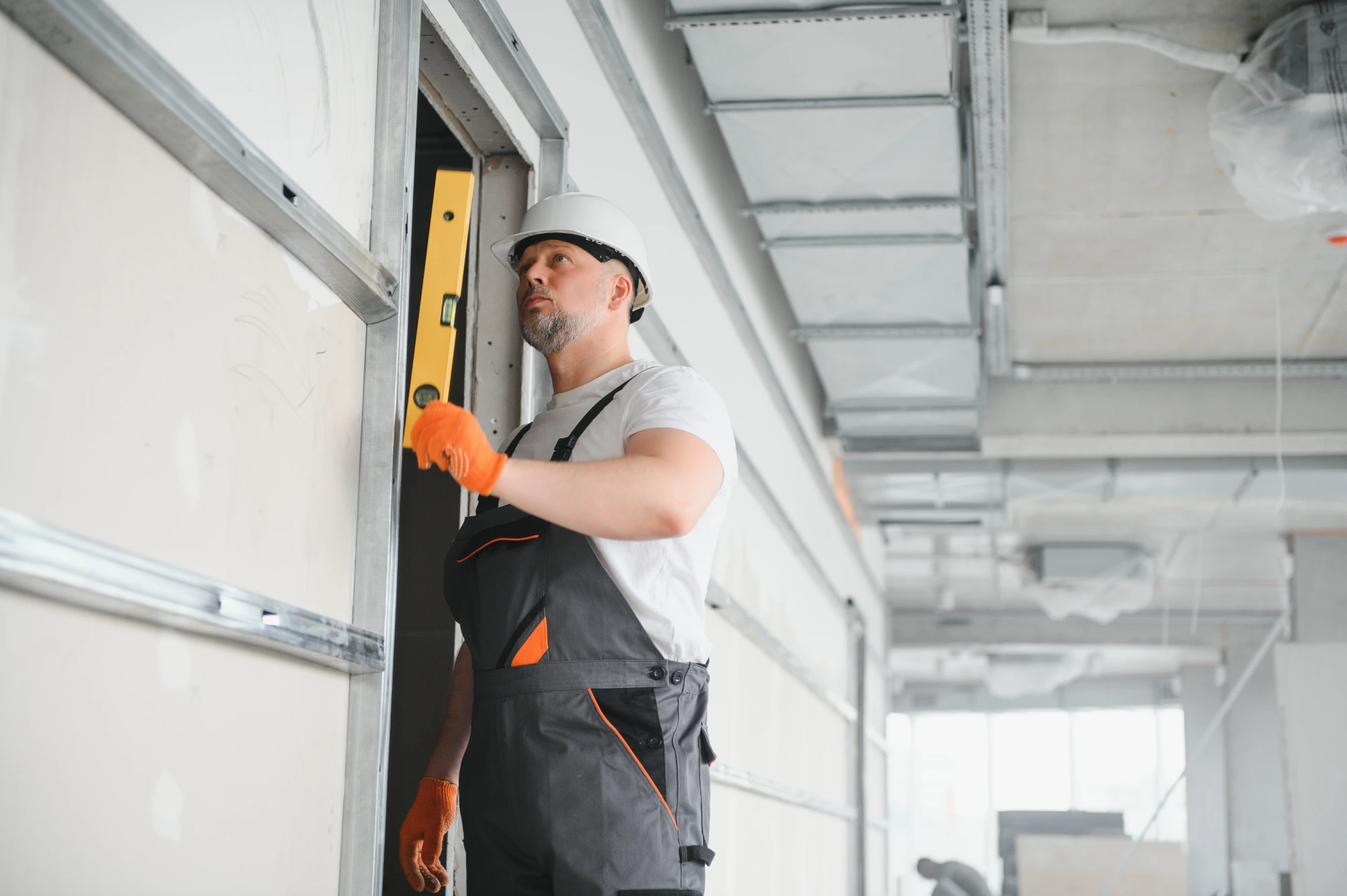 Construction worker in hard hat using a level on a wall frame