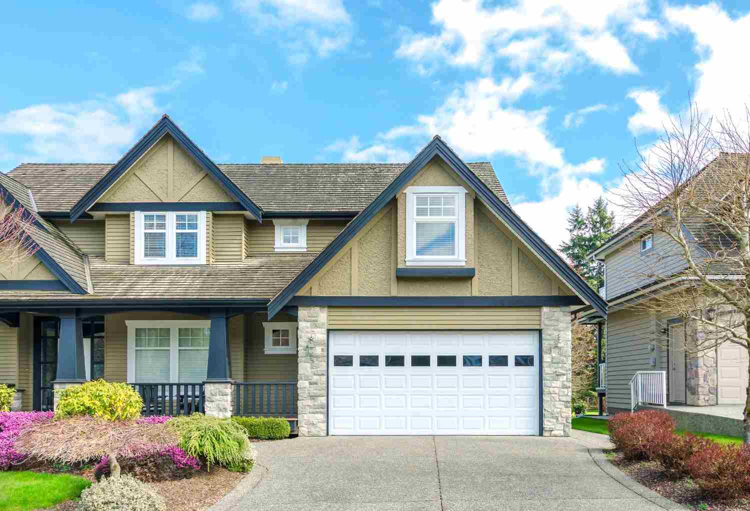 Front view of a modern house with a white garage door and landscaping.