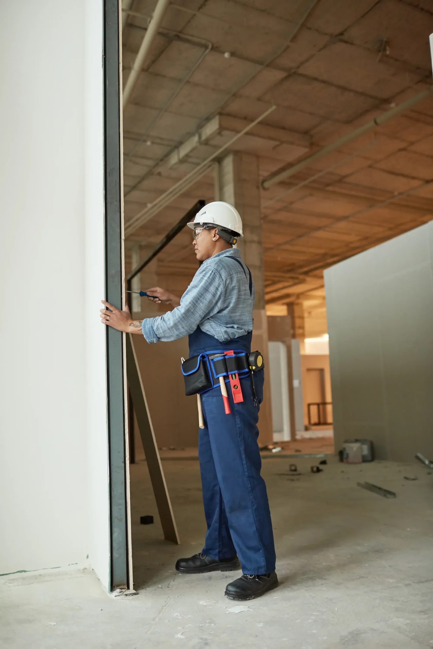 Construction worker installing a door frame with a screwdriver.