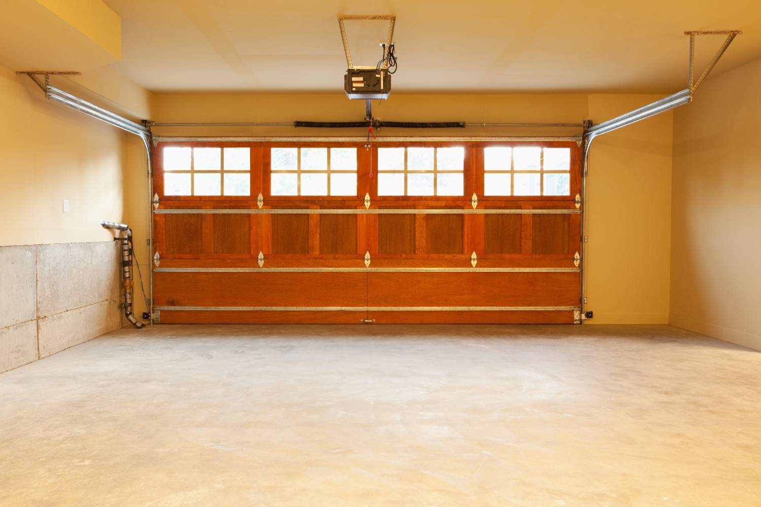 Empty garage with a wooden door and concrete floor.