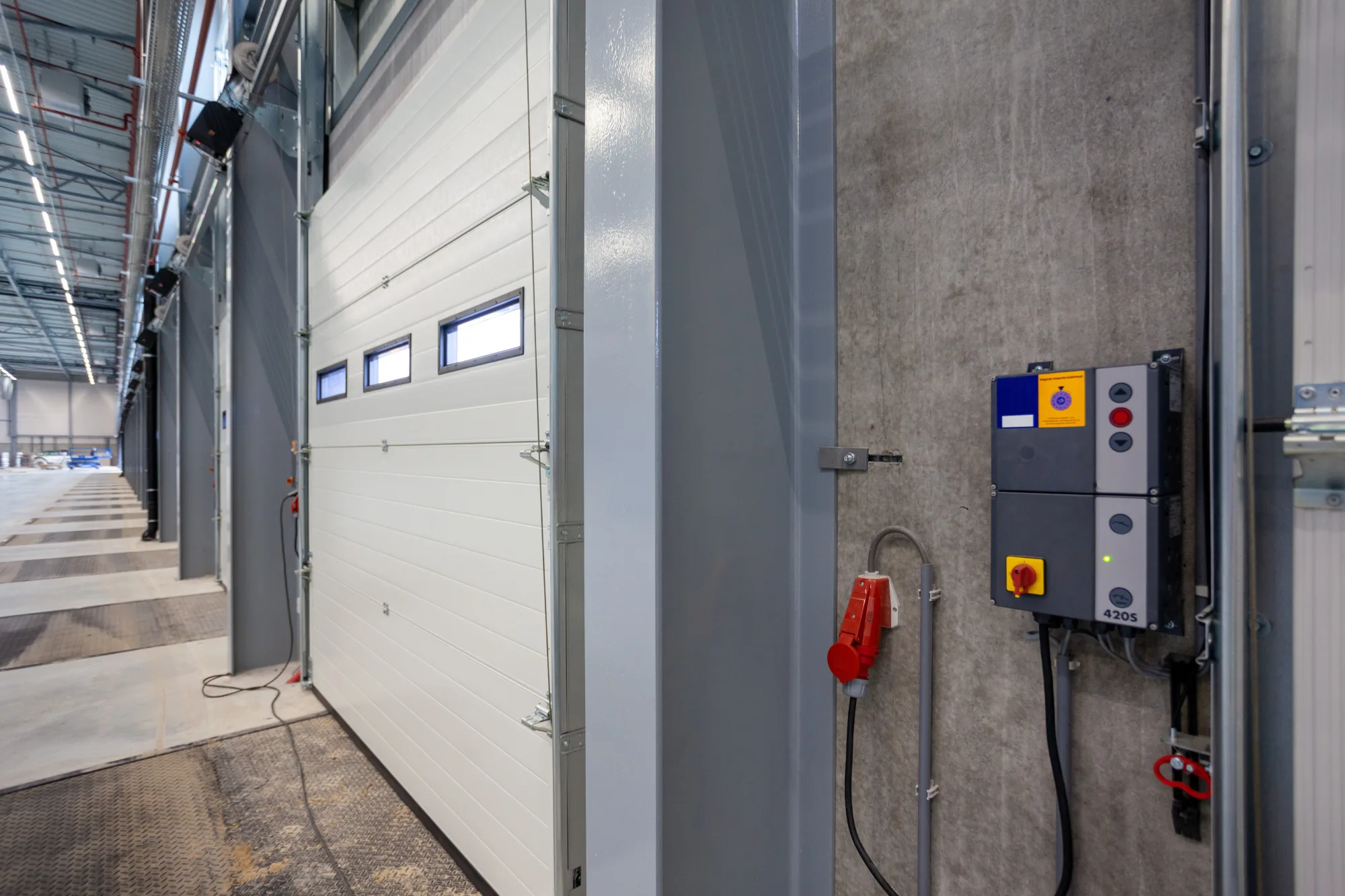 Industrial loading dock with a white sectional door and control panel.