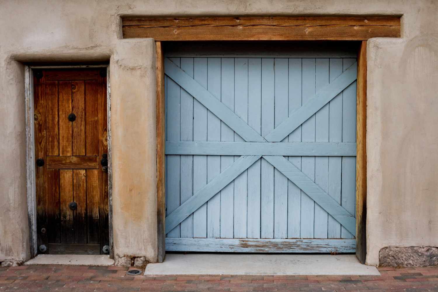 Two rustic doors side-by-side: one wooden, one light blue with an X-pattern.