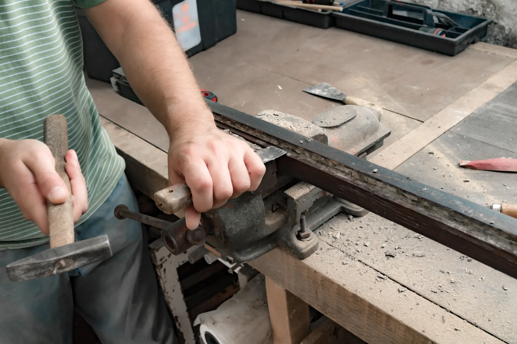 Person using a chisel and hammer on a wooden frame in a workshop.