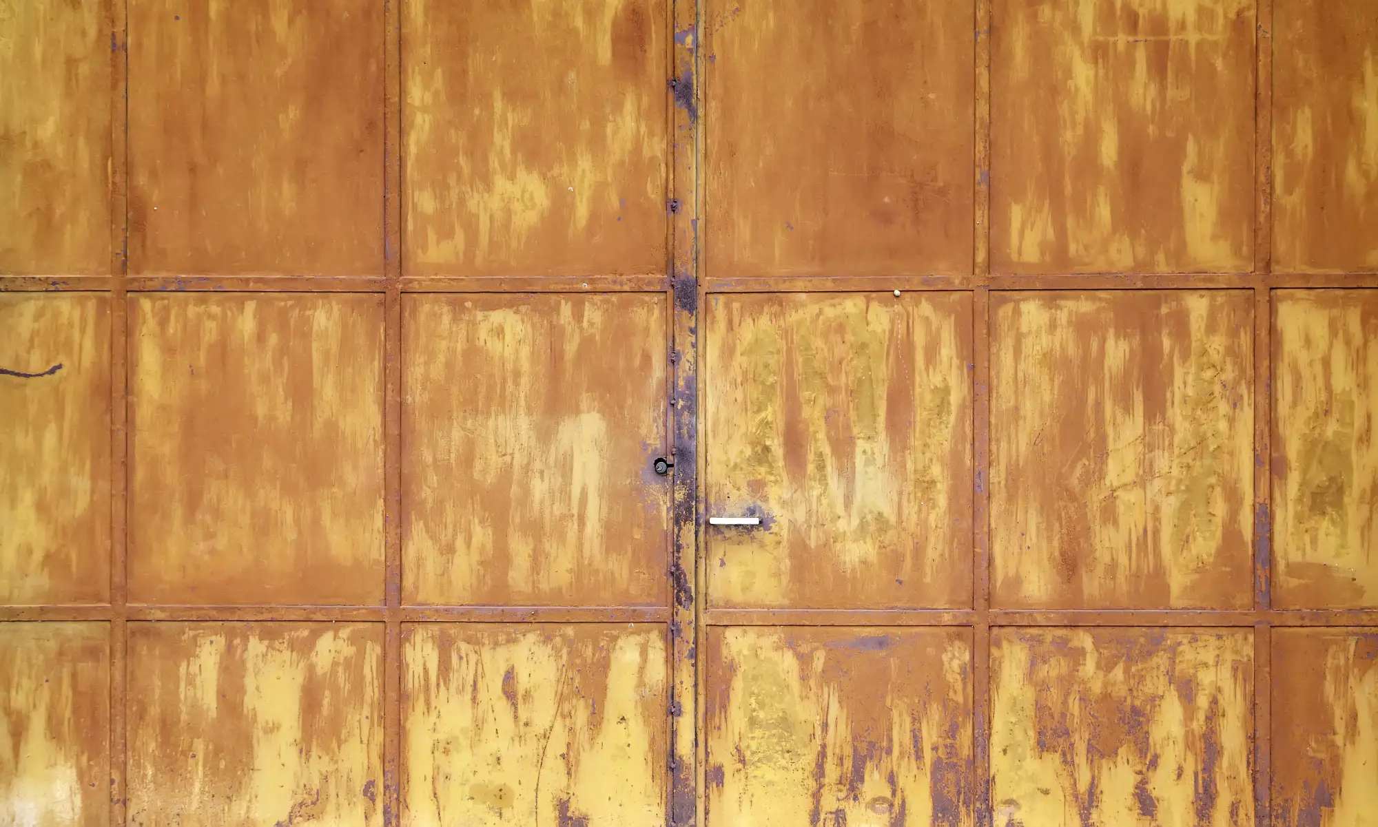 Close-up of a weathered and rusty metal door with a handle and lock.
