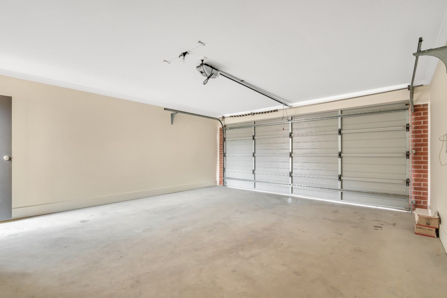 Empty garage with a closed sectional door and light beige walls