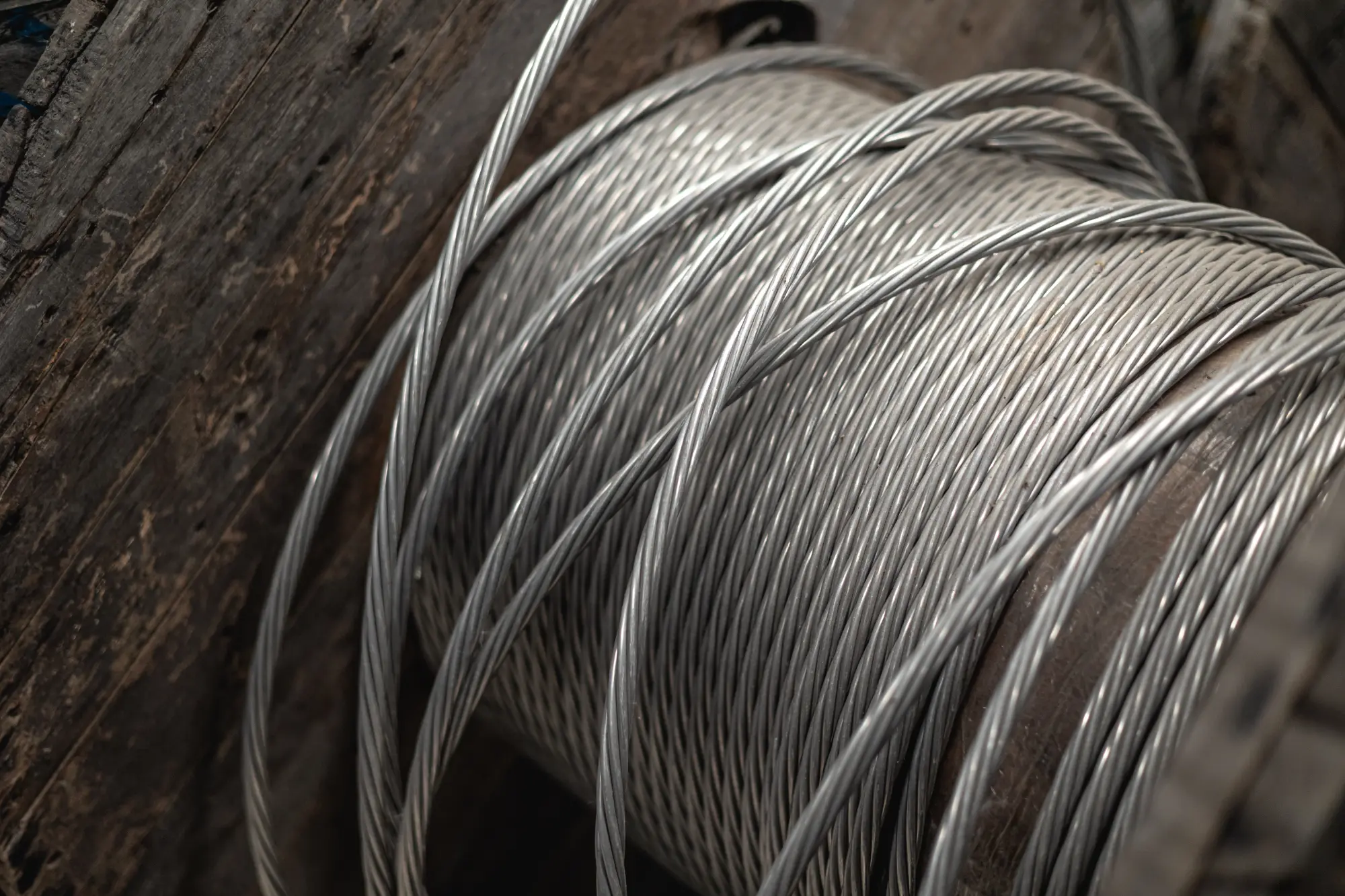 Close-up of a large wooden spool wound with thick metal cables.