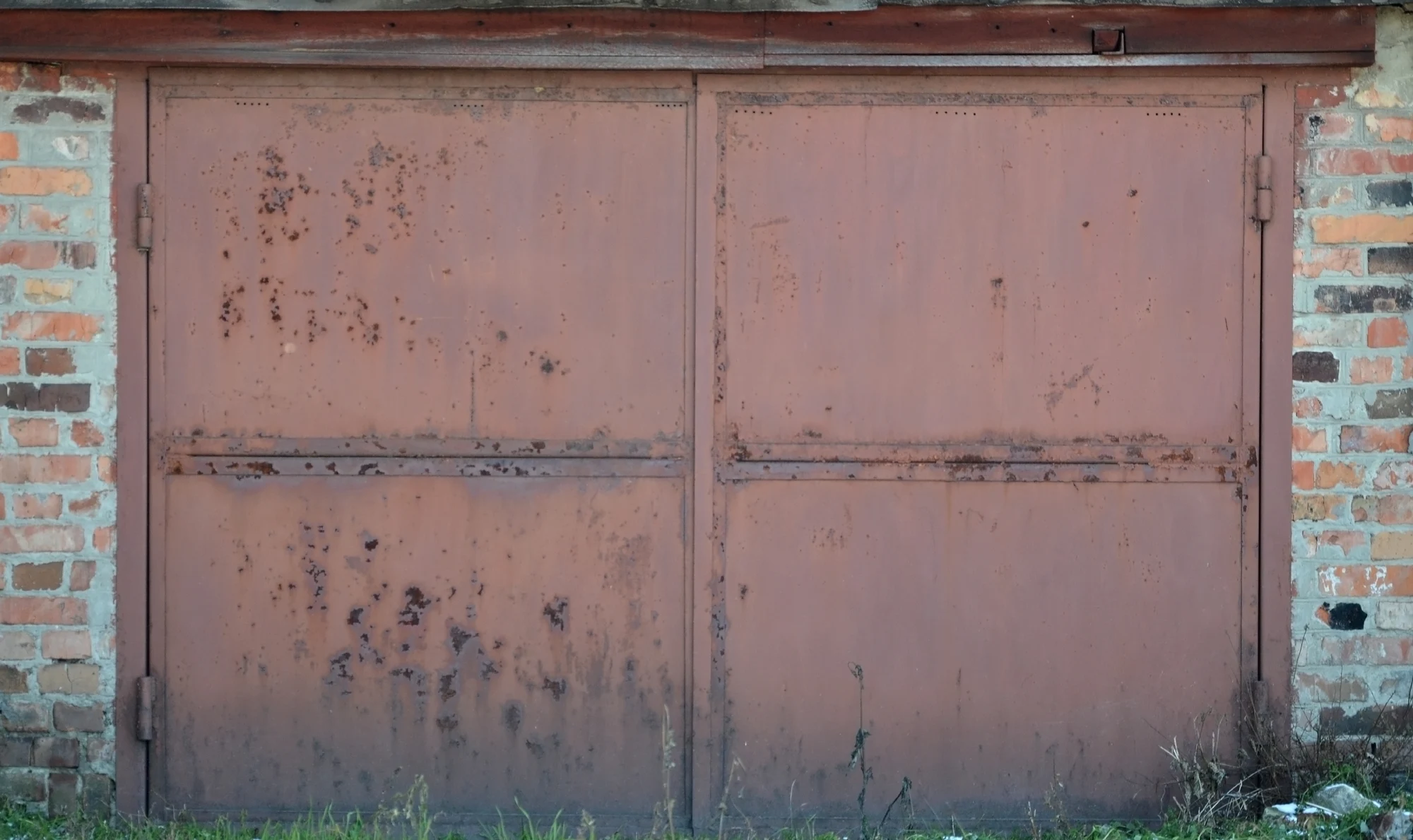 Rusty metal garage doors on a brick wall building
