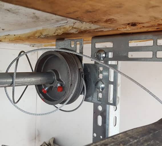 Close-up of a garage door cable drum and steel cable.