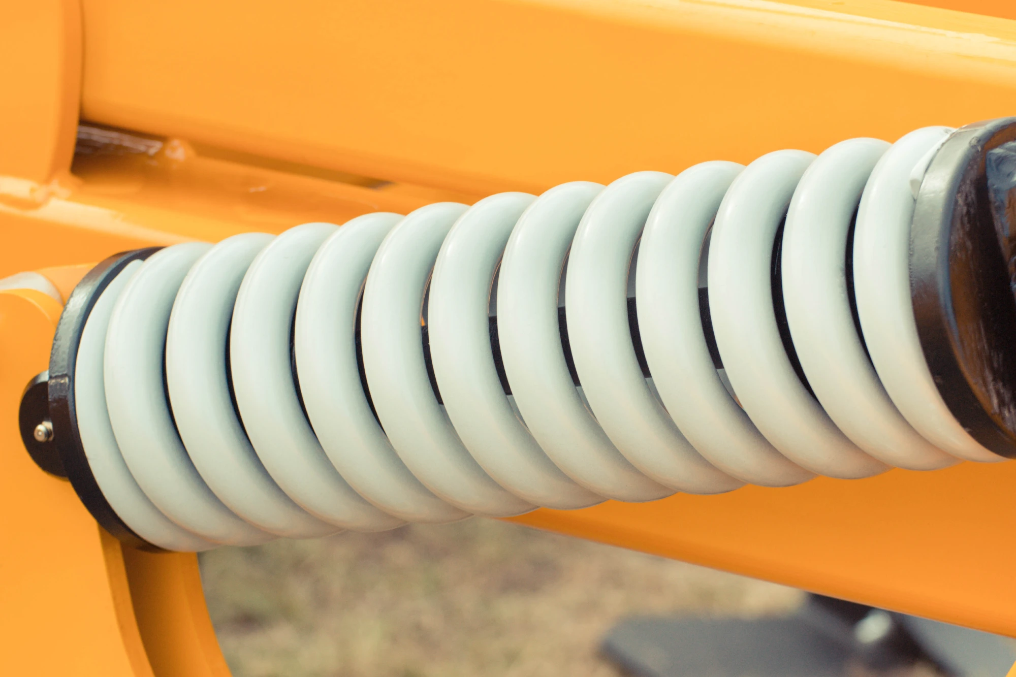 Close-up of a white spring on yellow machinery.