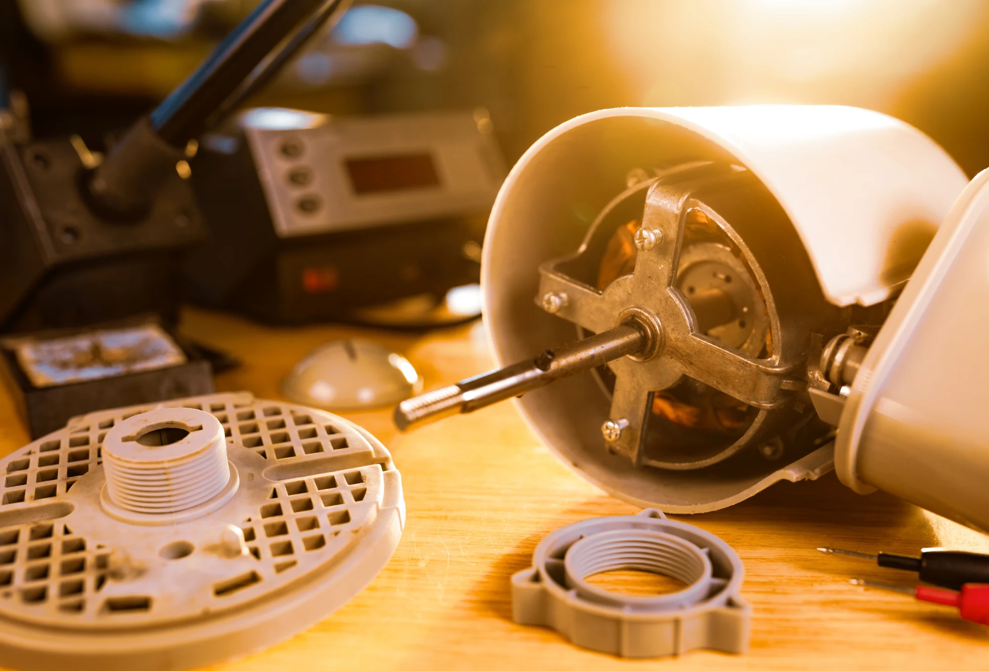 Disassembled fan motor with tools and components on a wooden surface.