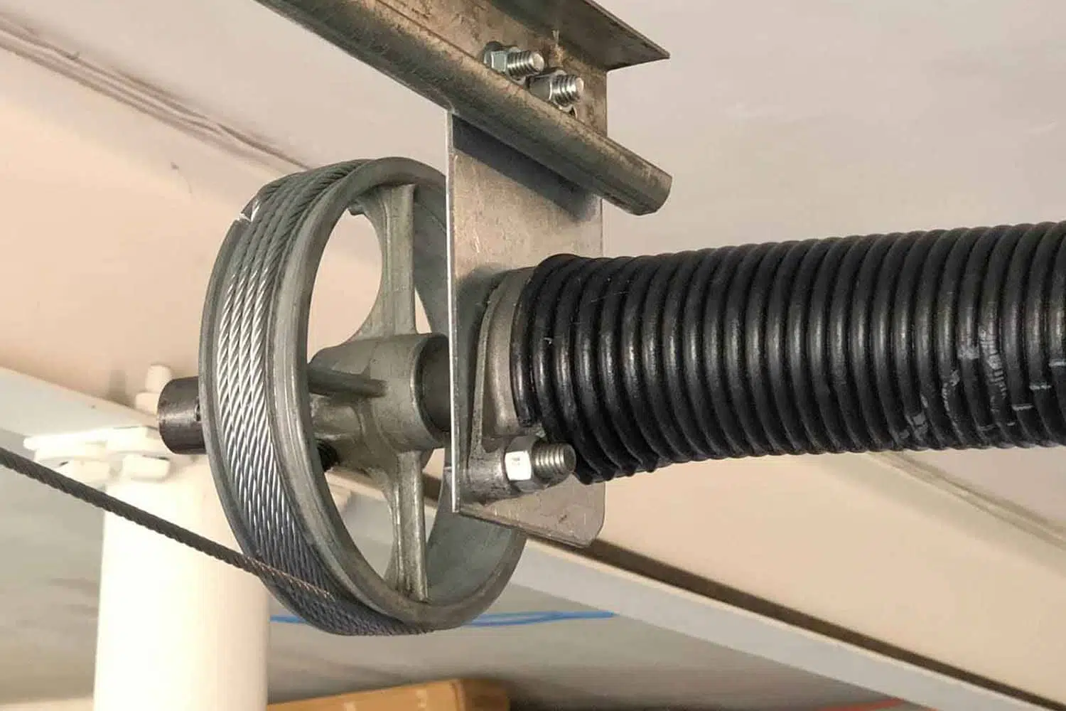 Close-up of a garage door torsion spring assembly with a pulley and cable.