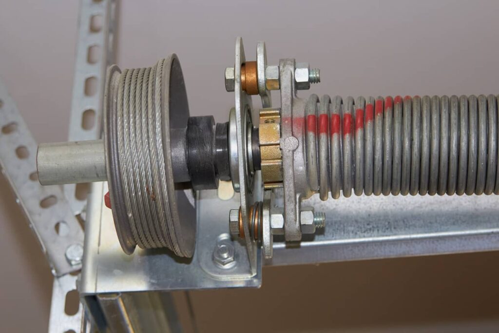 Close-up of a garage door torsion spring system with cable drum.