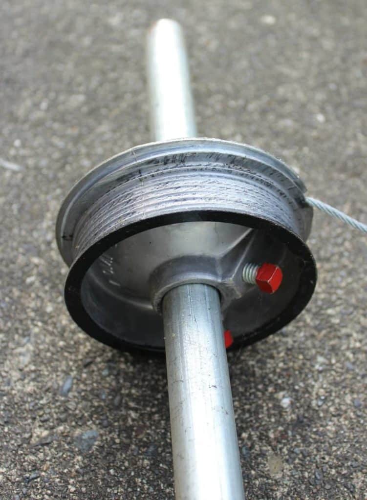 Close-up of a garage door cable drum on a metal shaft.