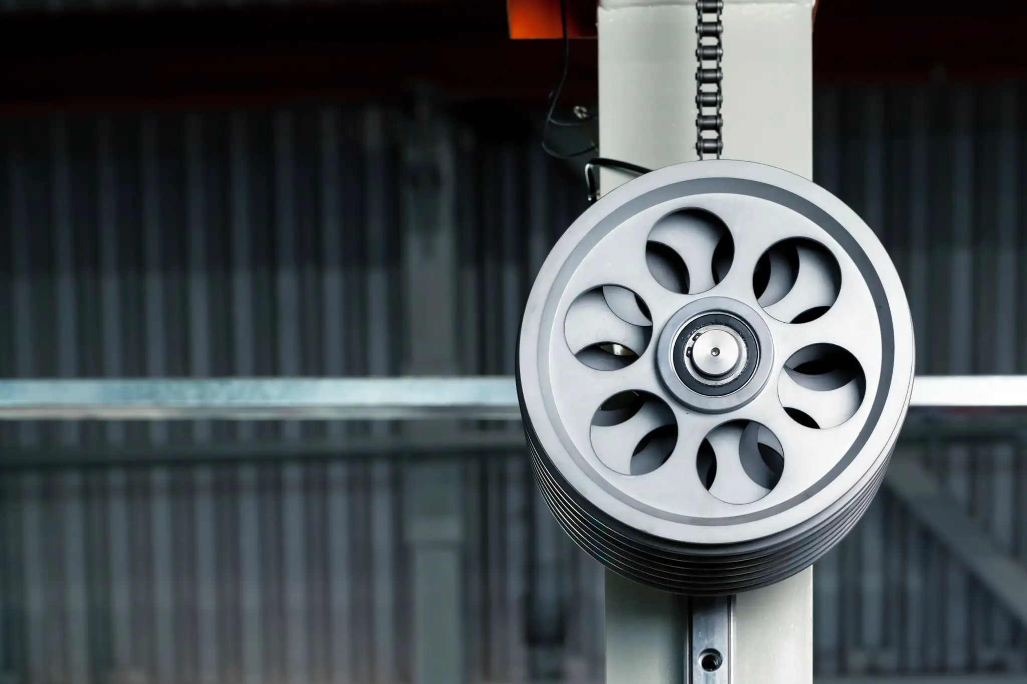 Close-up of a metal pulley wheel with a chain, industrial setting.